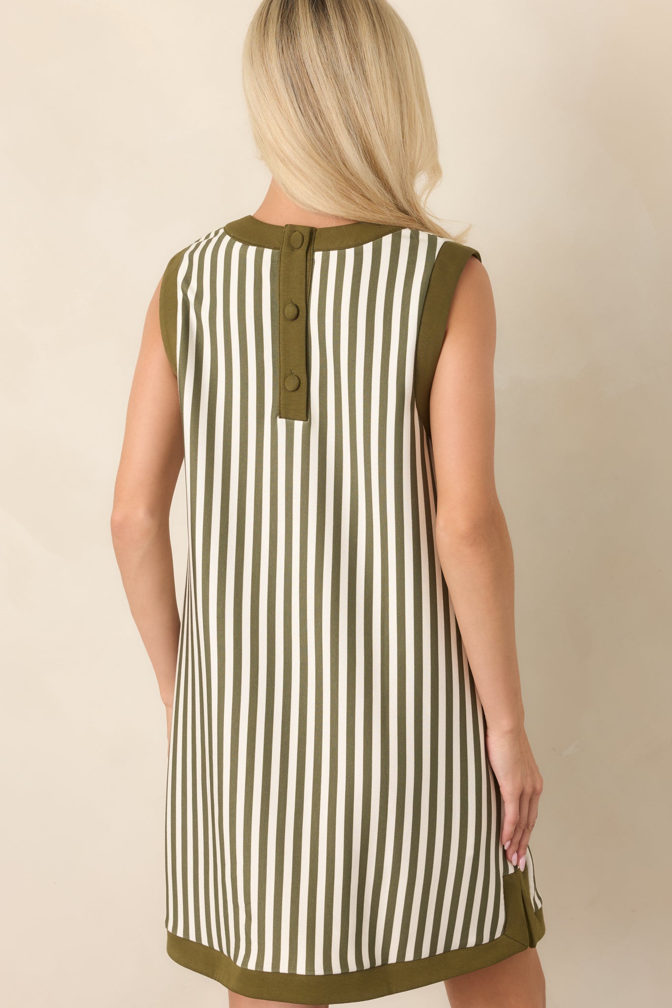 Rear view of the olive and ivory striped mini dress, highlighting the sleeveless straight silhouette and covered buttons at the back neckline.