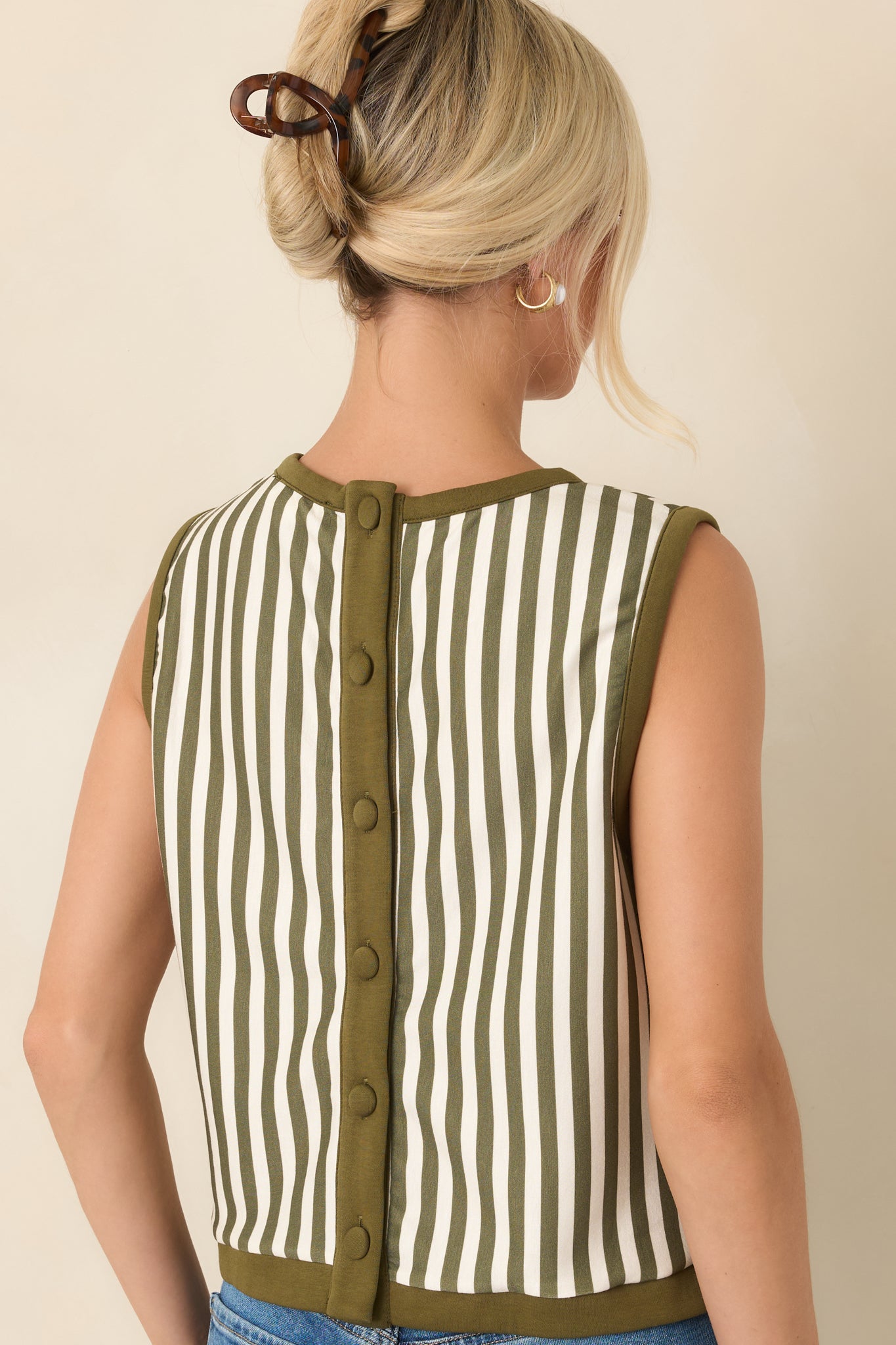 Rear view of the olive and ivory striped sleeveless top, highlighting its cropped silhouette and button-down detail along the back.