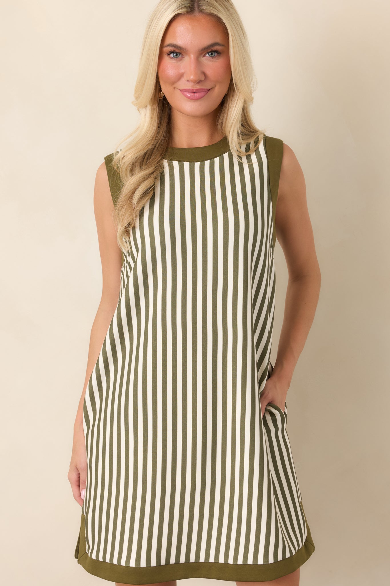 Vertical olive and ivory stripes extend across the relaxed mini dress, creating a clean, streamlined look with contrasting trim.