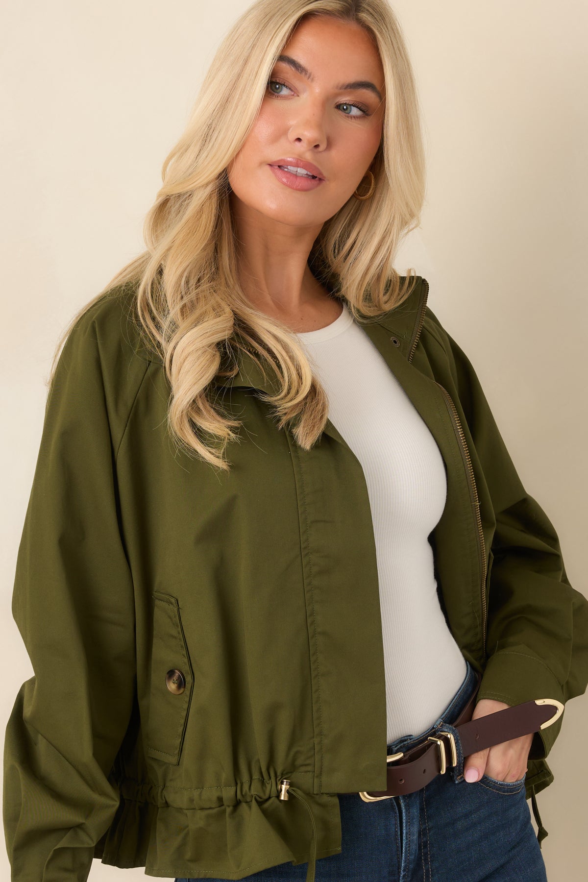 Olive jacket features a full-length zipper, clean front seams, and practical snap-accented details.