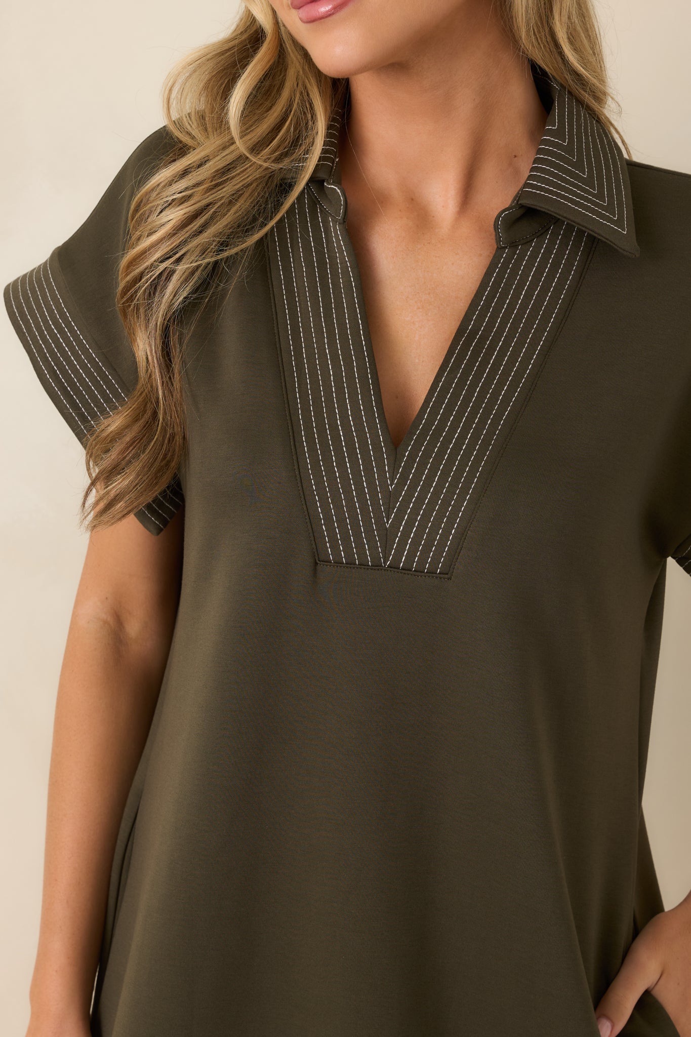 Close-up of the olive knit dress highlighting the collared V-neckline, contrast pinstriped trim, and soft fabric texture.