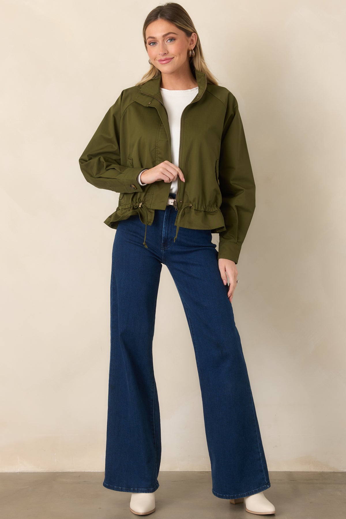 Lined olive jacket with flap pockets, a zip closure, and a softly ruffled lower hem.