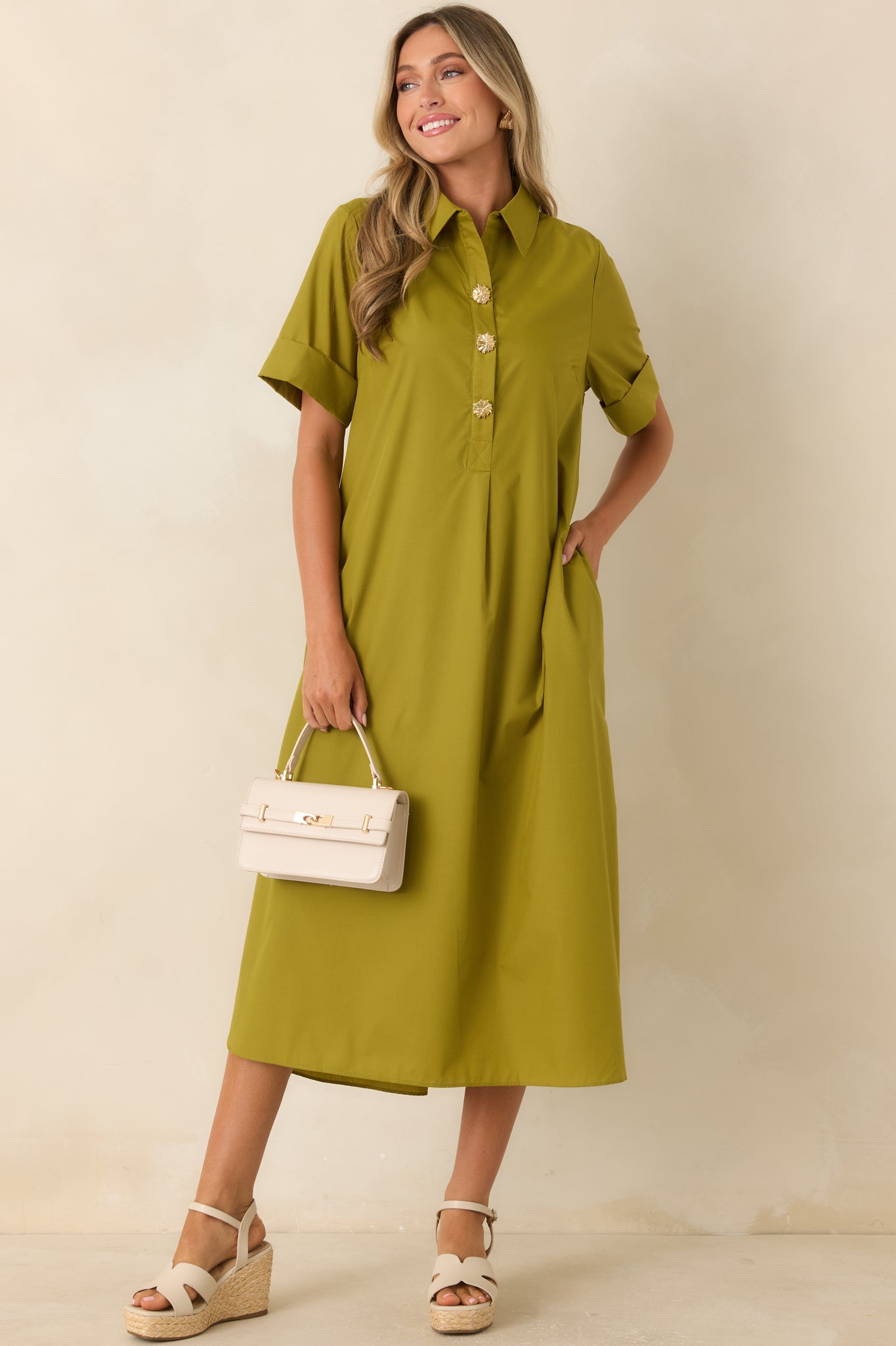 Relaxed olive maxi dress featuring statement gold floral buttons, rolled sleeves, side slits, and an effortlessly elegant silhouette.