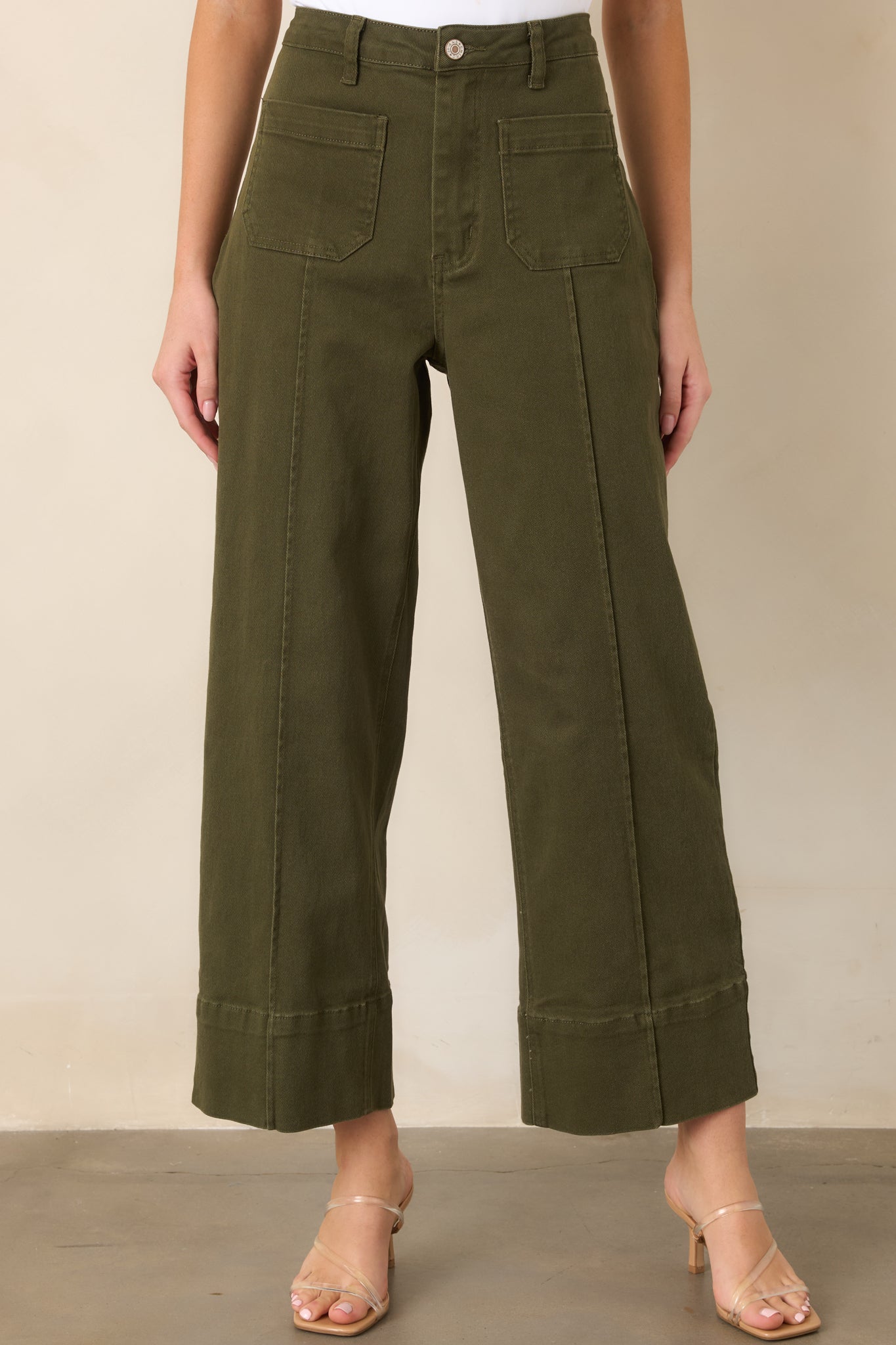 Close view of the olive pants highlighting the high-rise waistband, belt loops, and oversized front patch pockets.