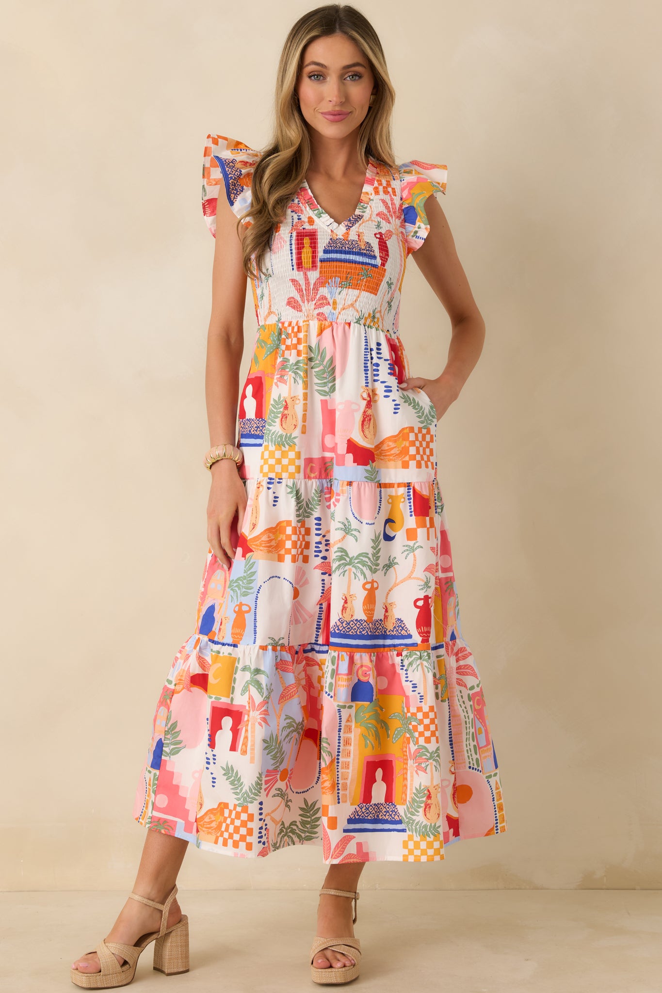 Front view of an orange and pink multi maxi dress with a V-neckline, flutter sleeves, and smocked bodice.