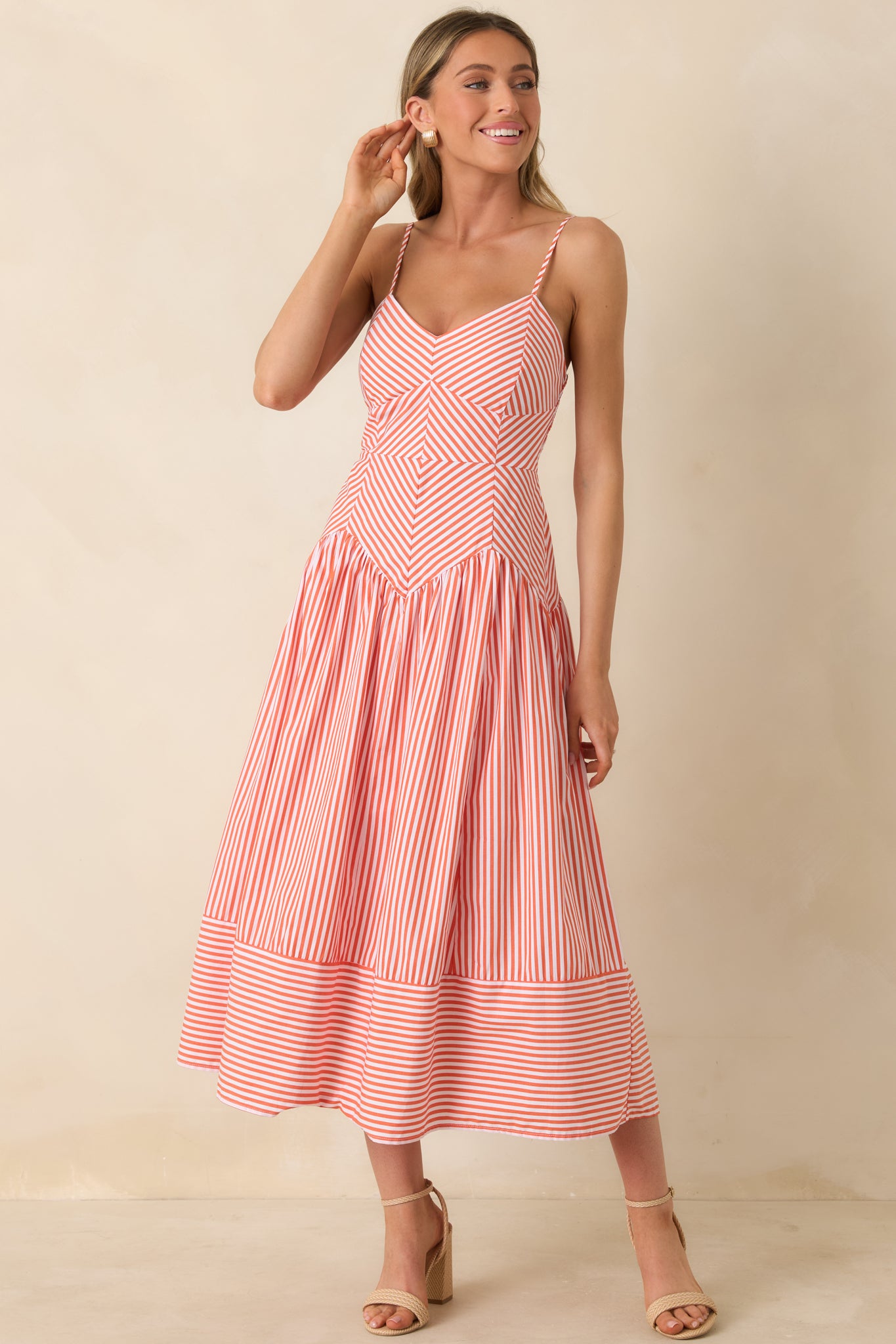 Orange and white striped midi dress with structured top and relaxed skirt.
