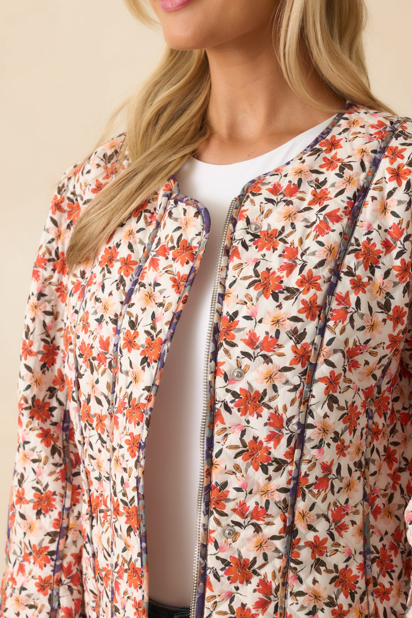 Detailed view of the orange multicolor floral print, quilted stitching, and piping accents on the jacket.