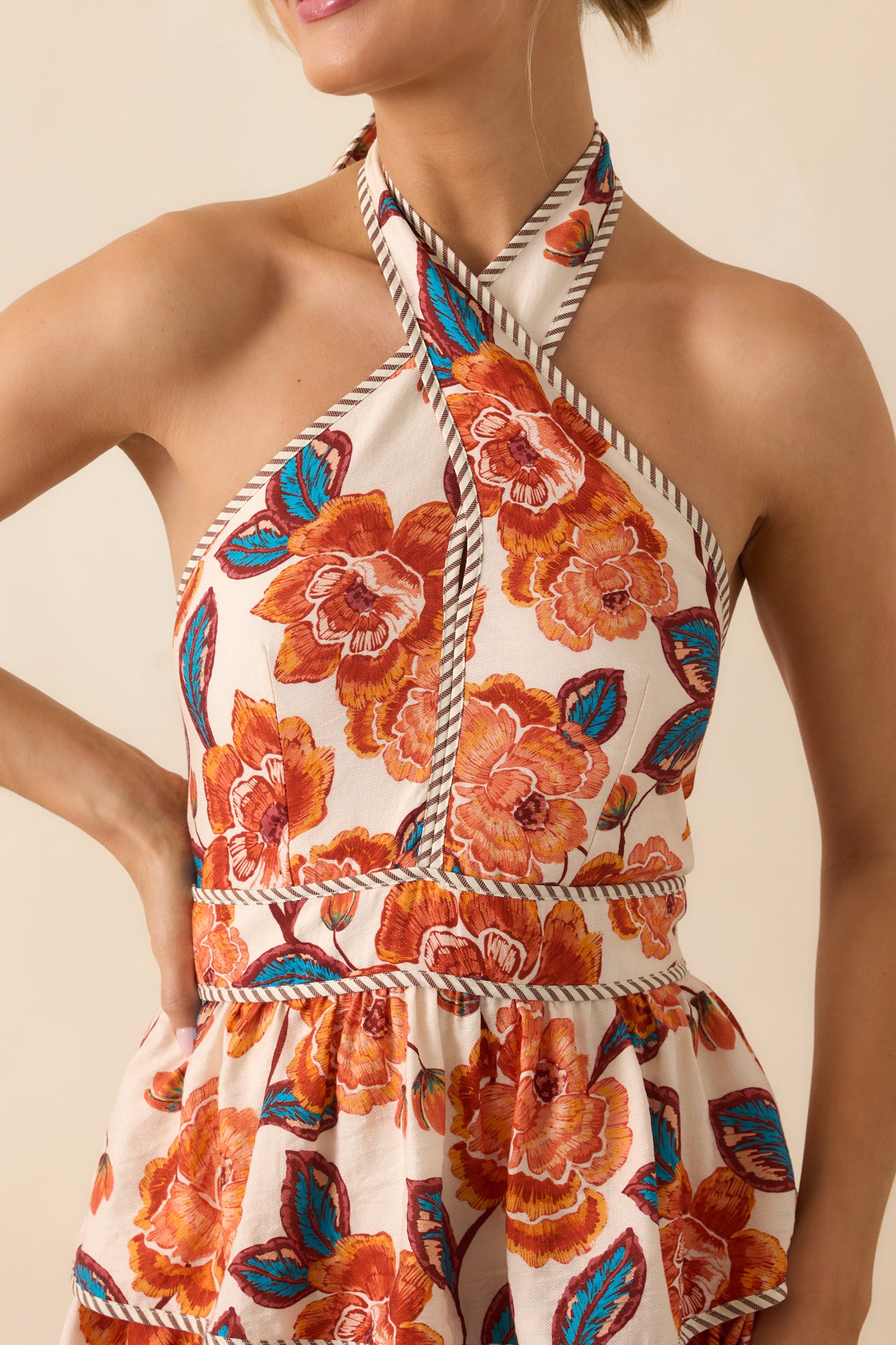 Detailed view of the criss-cross halter neckline and self-tie bow closure on the orange floral maxi dress.