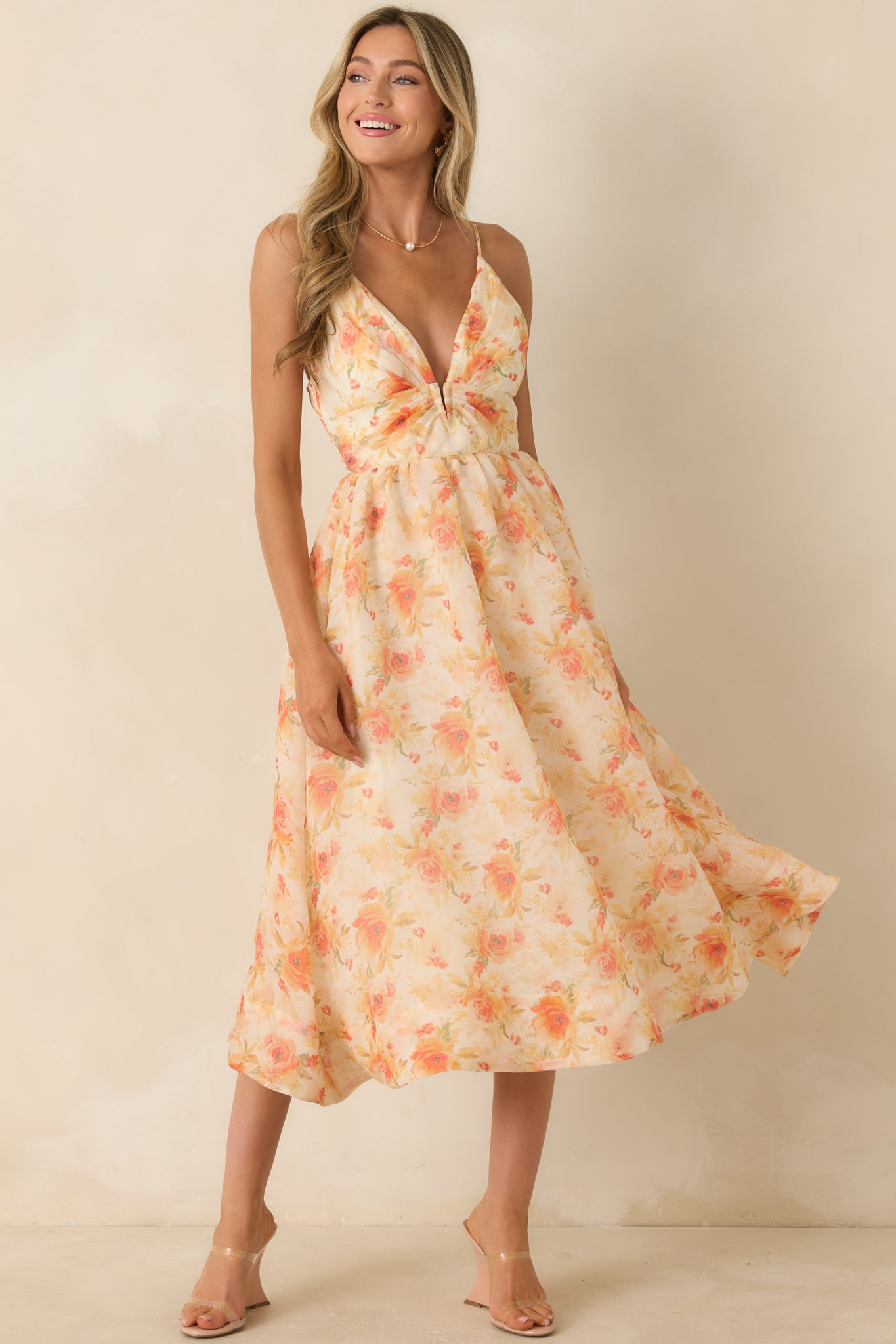 Orange floral midi dress featuring a plunging V-neckline, adjustable spaghetti straps, and a flowy midi-length skirt.