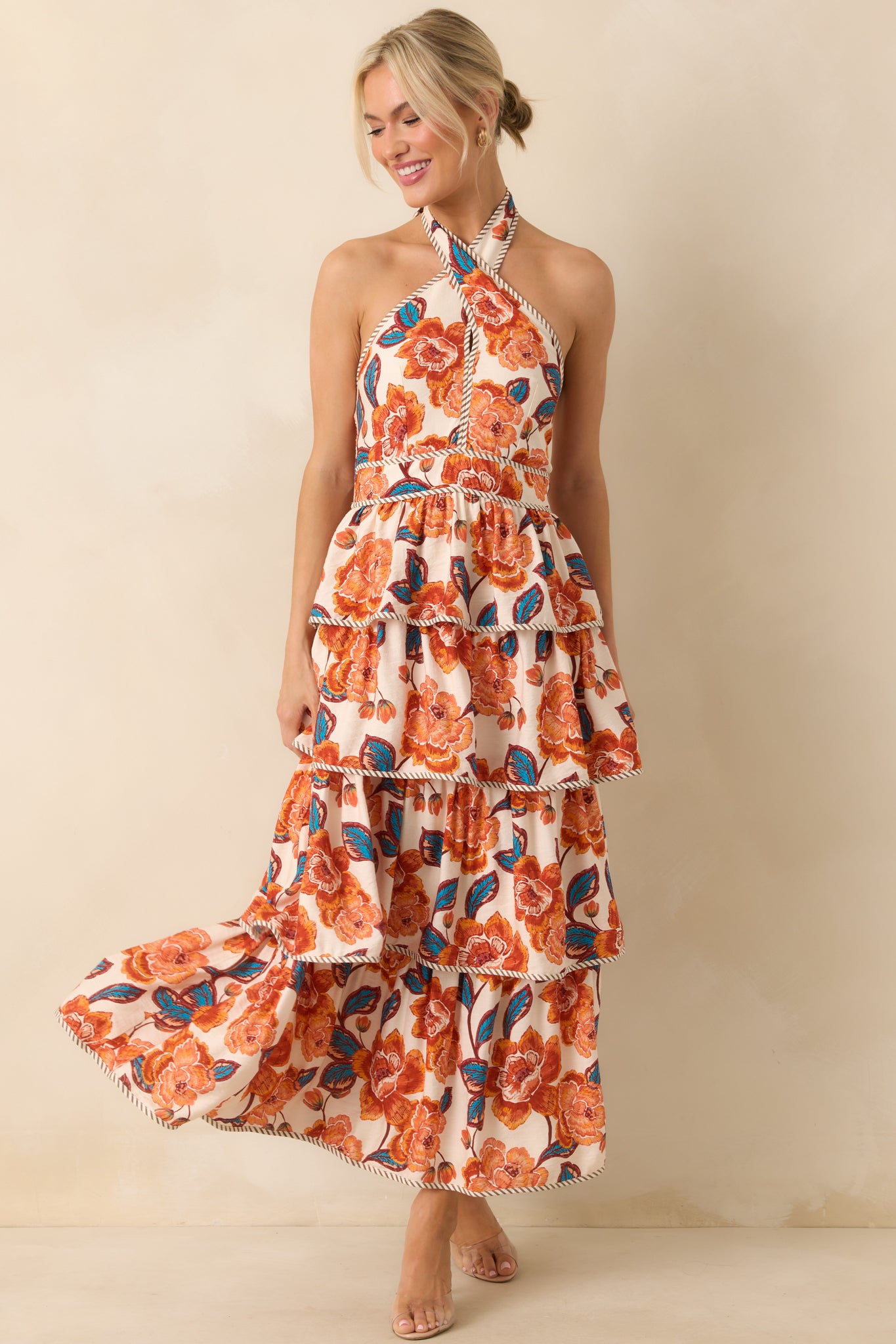 Orange maxi dress with a multicolor floral print and criss-cross halter neckline with self-tie bow.