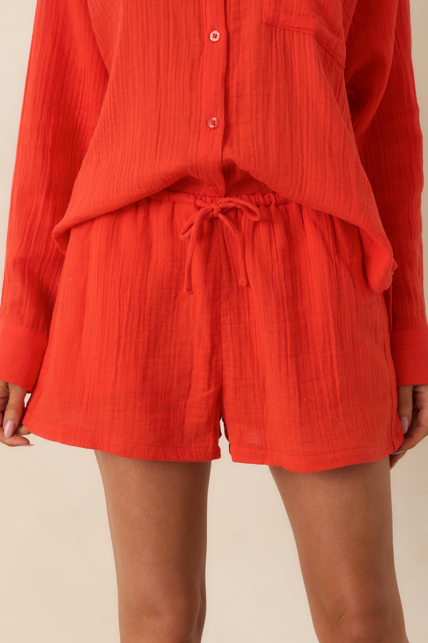 Orange-red shorts highlighting the adjustable drawstring waistband, airy gauze fabric, and relaxed fit.