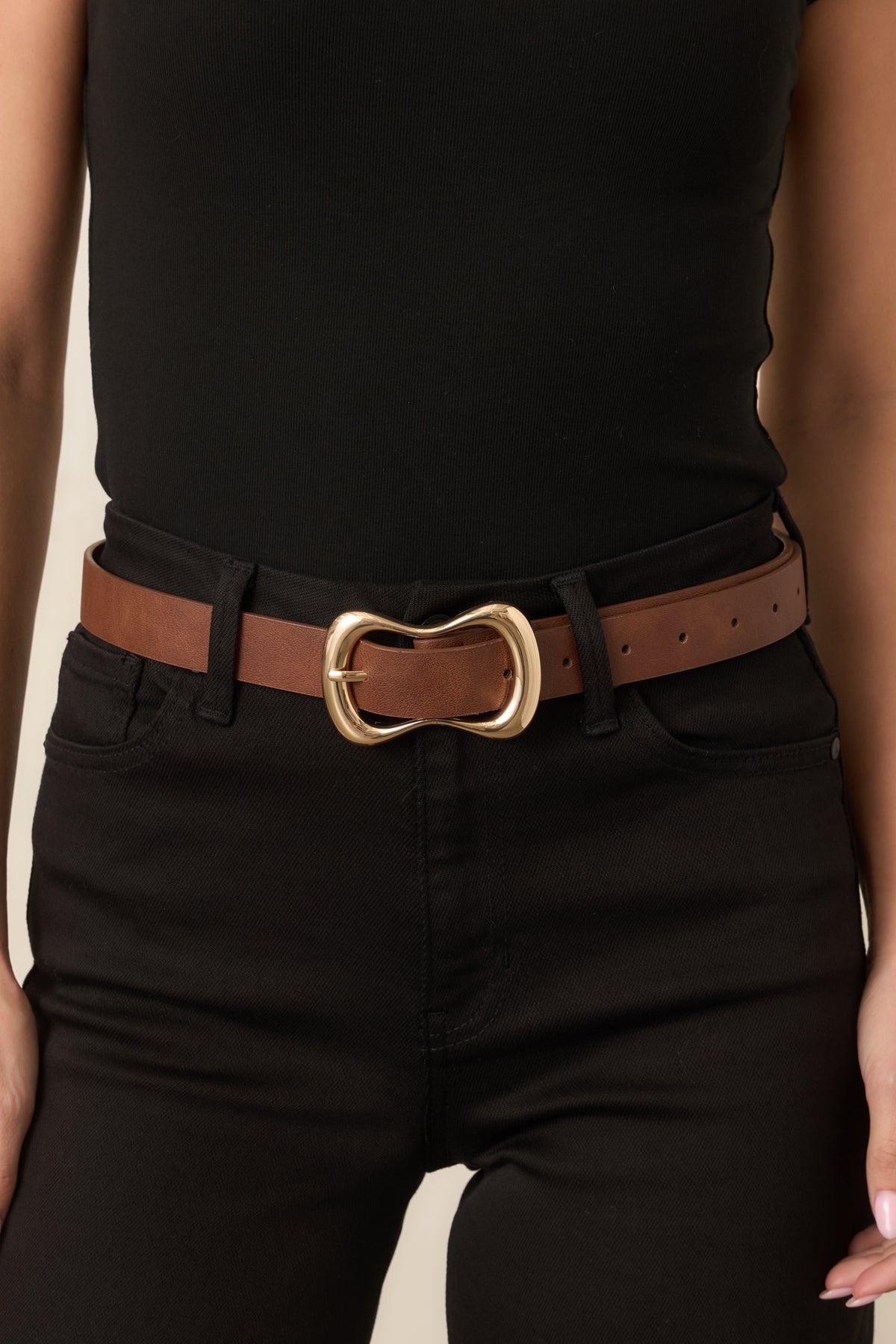 Close detail of the organic gold-tone buckle and smooth cognac strap.