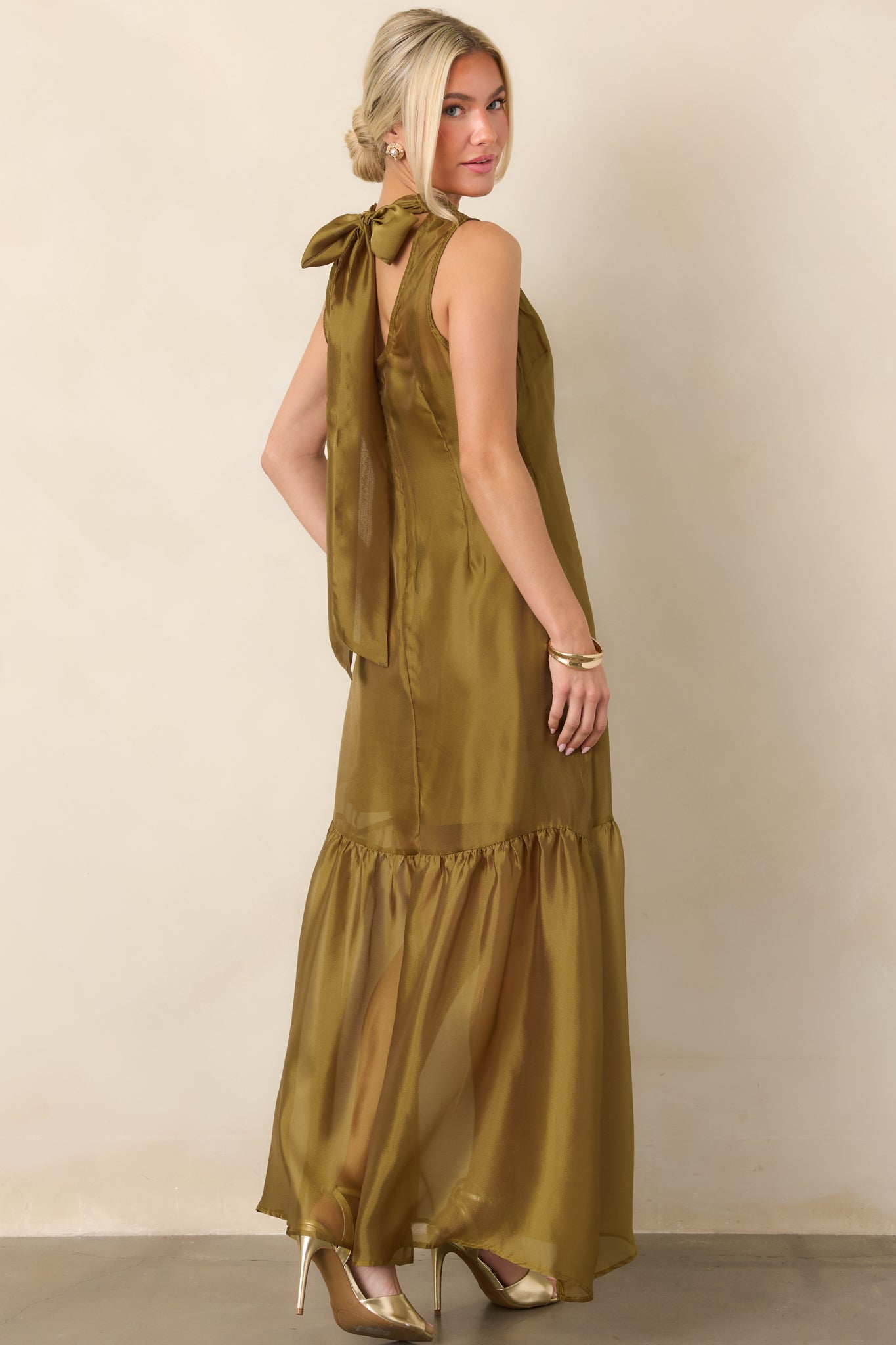 Rear view of the sheer organza maxi dress showing the high neckline, dramatic back tie, keyhole opening, concealed zipper, and flowing gathered skirt.
