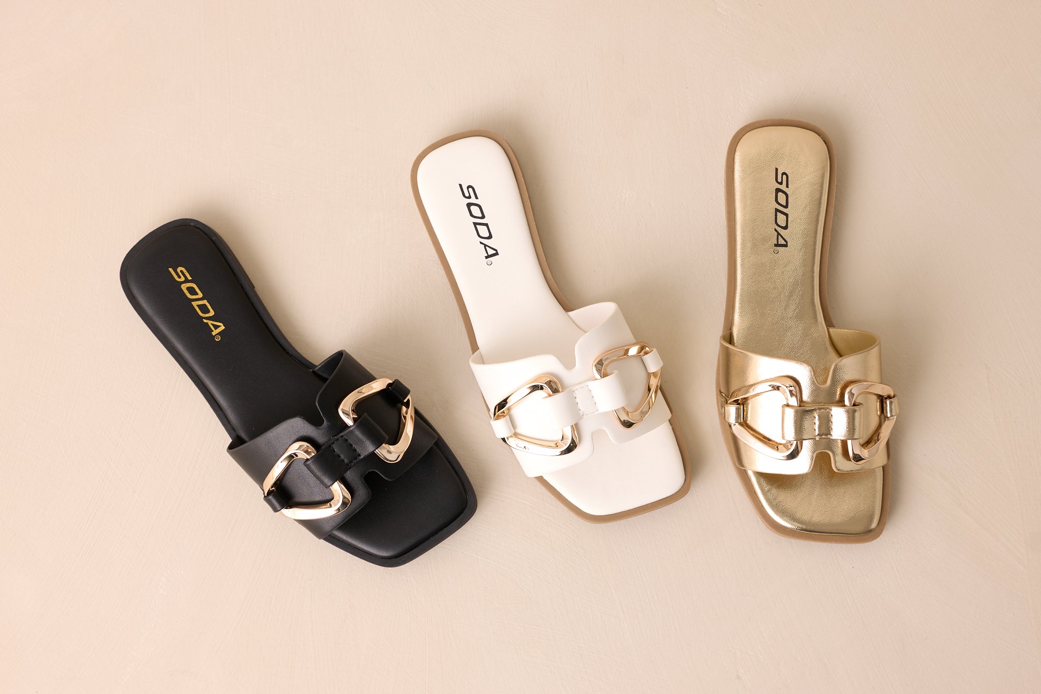 An overhead shot showcasing all three sandal colors featuring black, white and gold. 