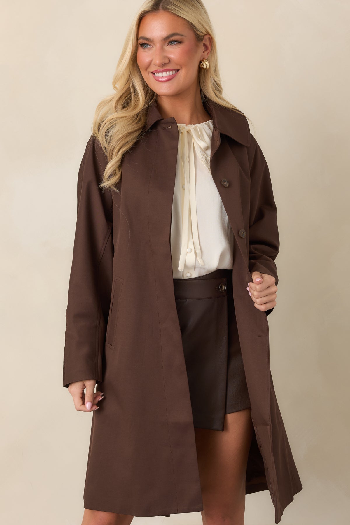 Oversized brown coat showcasing the pointed collar and polished front finish.

