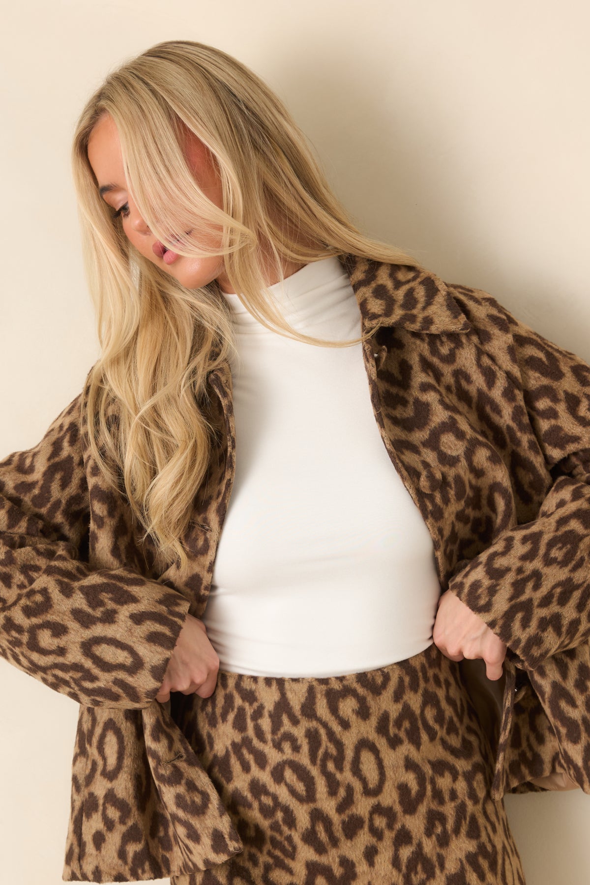 Oversized covered buttons run down the front beneath the spread collar of the leopard jacket.