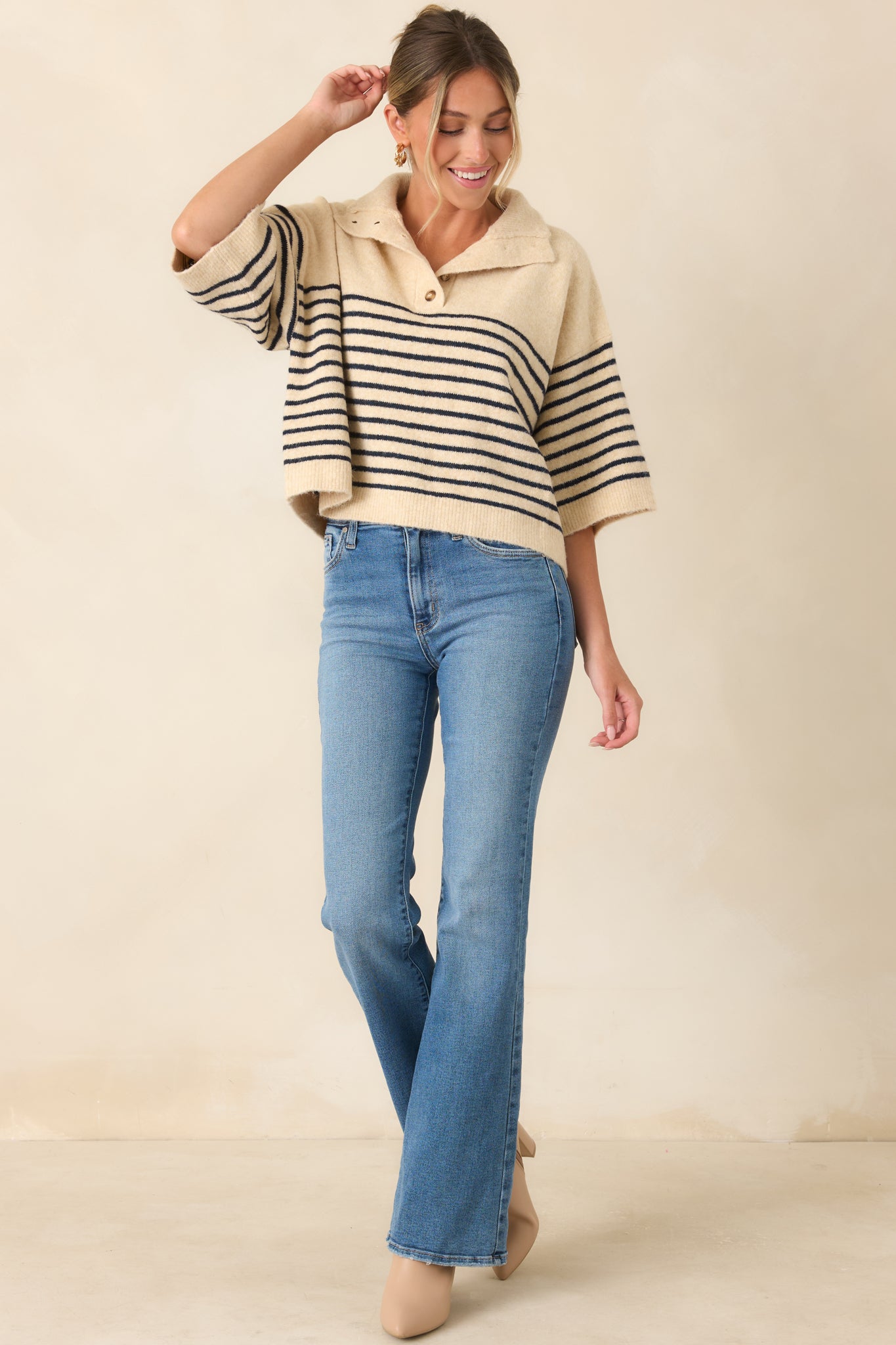 Oversized knit top featuring navy stripes on an ecru base, a wide collared neckline, and a partial button placket.