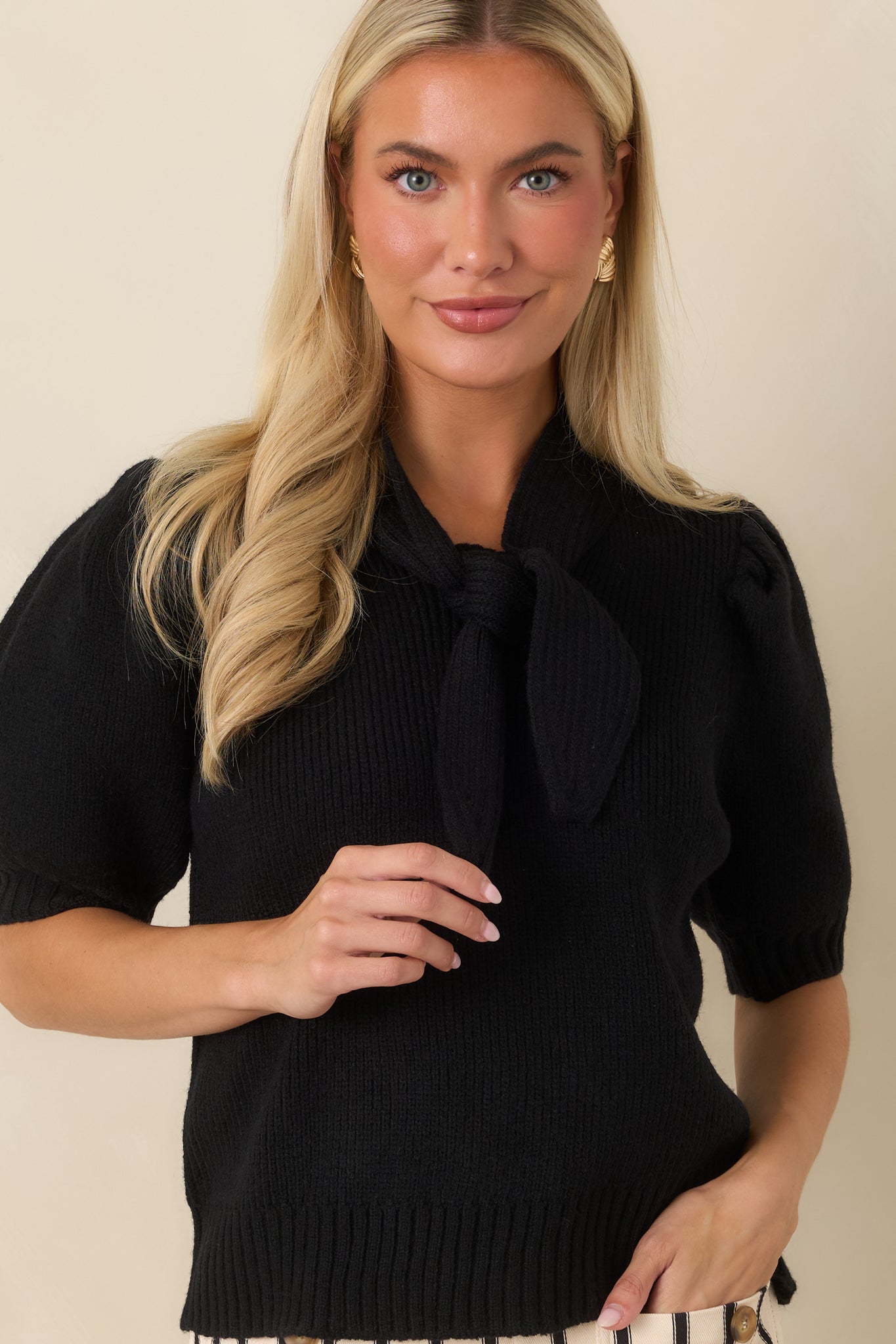 Detailed view of the oversized self-tie neckline showcasing the elegant bow detail and ribbed knit texture.
