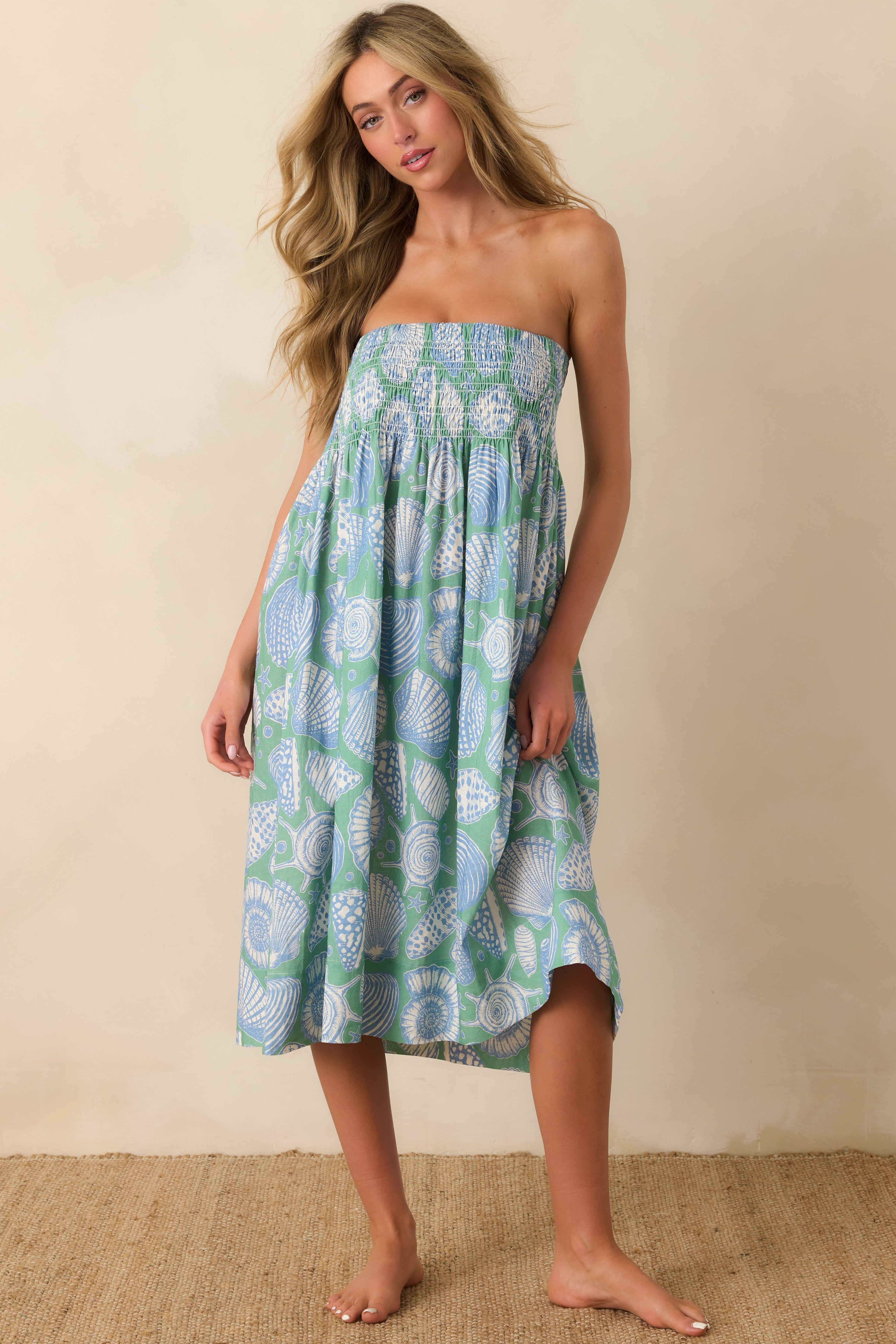 Full view of the piece being styled as a dress, showcasing its smocked bodice, midi length, and shell print.