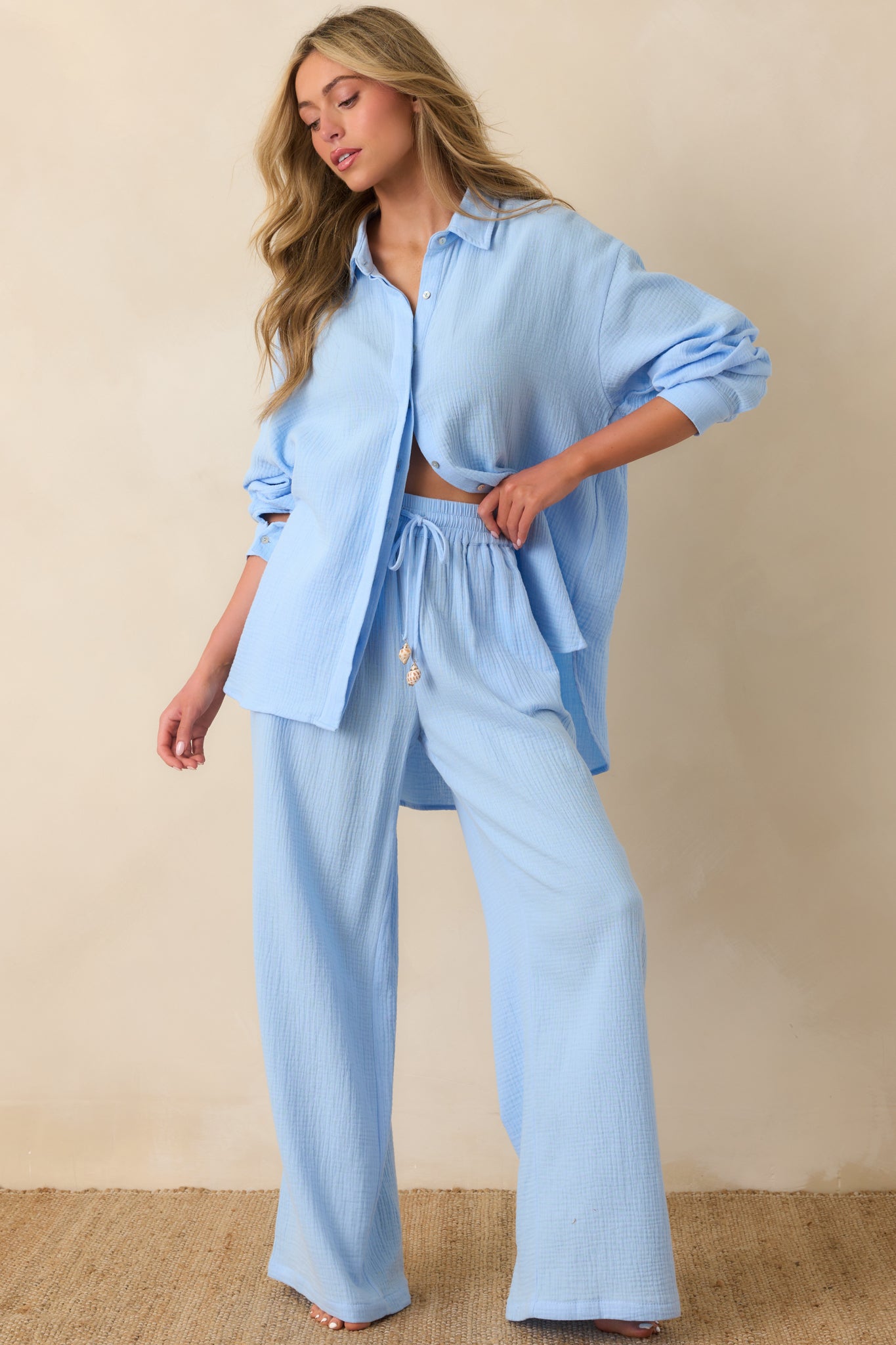 Full shot of the blue gauze-style shirt featuring long sleeves, button cuffs, and high-low hemline.