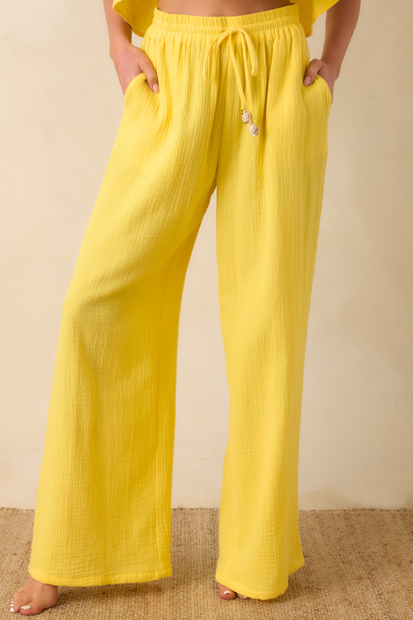 Close view of yellow pants highlighting elastic waistband and adjustable drawstring.

