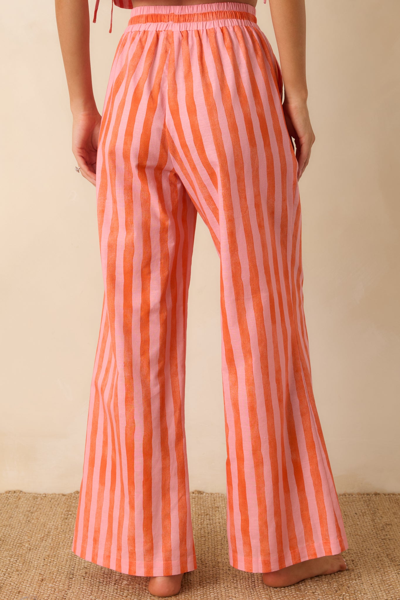 Rear view of the pink and orange striped pants featuring a comfortable elastic waistband and flowing wide leg silhouette.