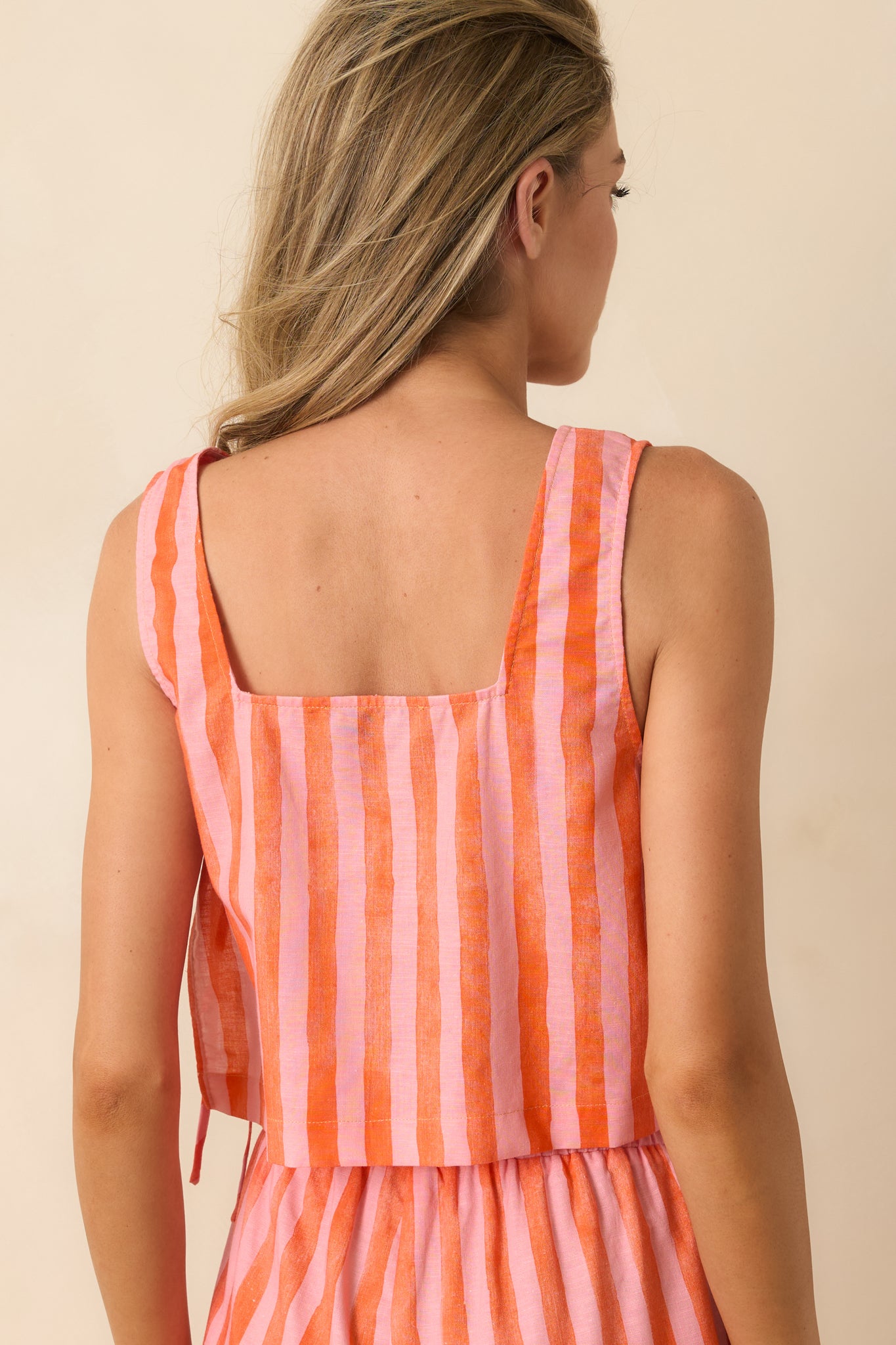 Rear view of the pink and orange striped crop top featuring a sleeveless silhouette and relaxed cropped fit.