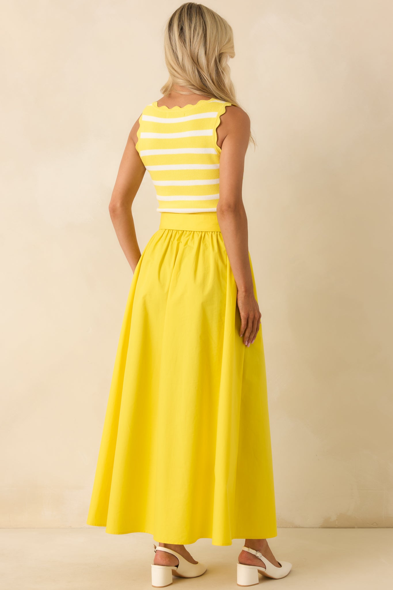 Rear view of yellow midi dress with stripe knit top, scalloped hem accents, and smooth flowing skirt.

