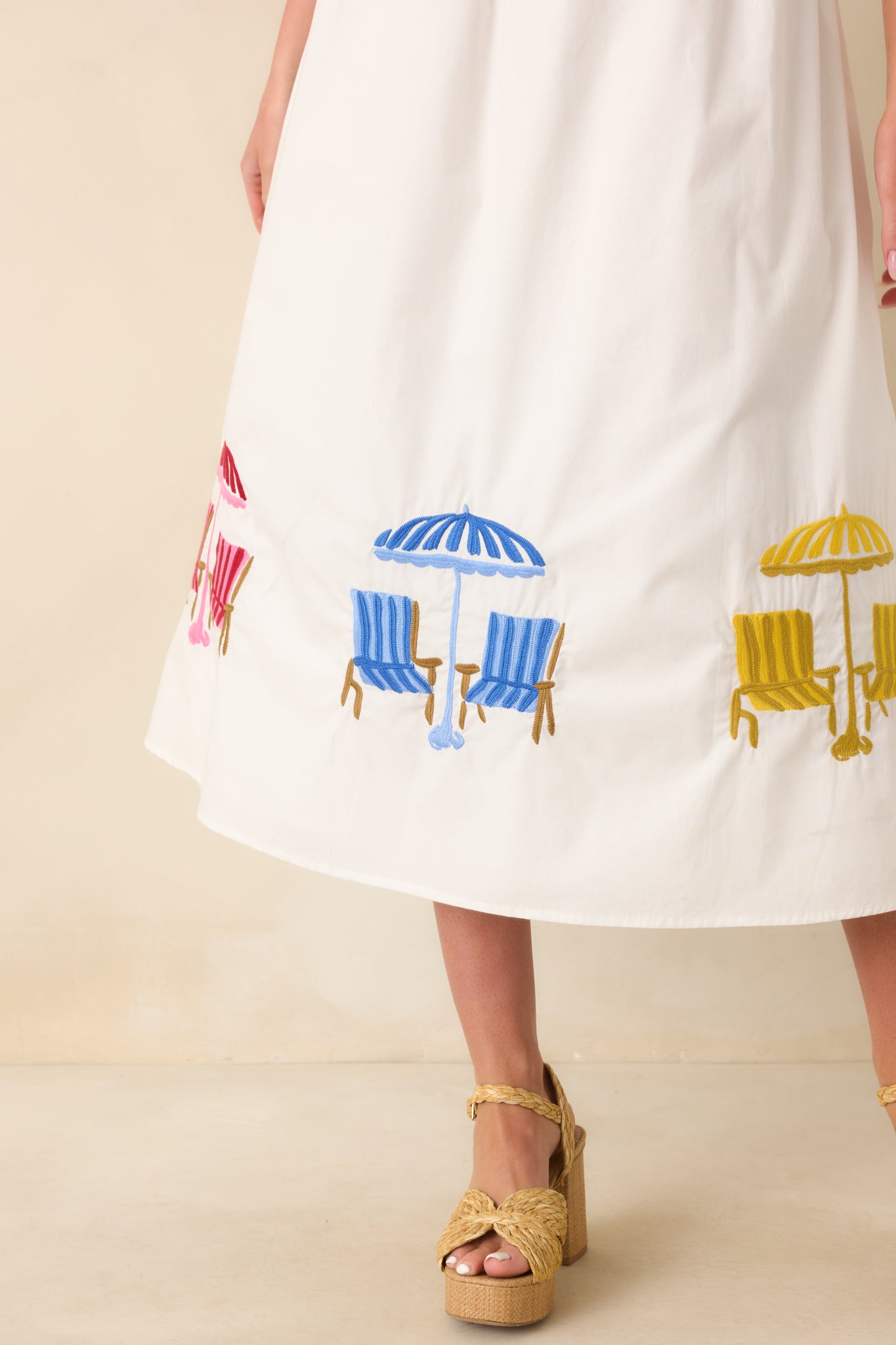 Close-up view of the embroidered beach umbrellas, lounge chairs, and detailed stitching along the hem.