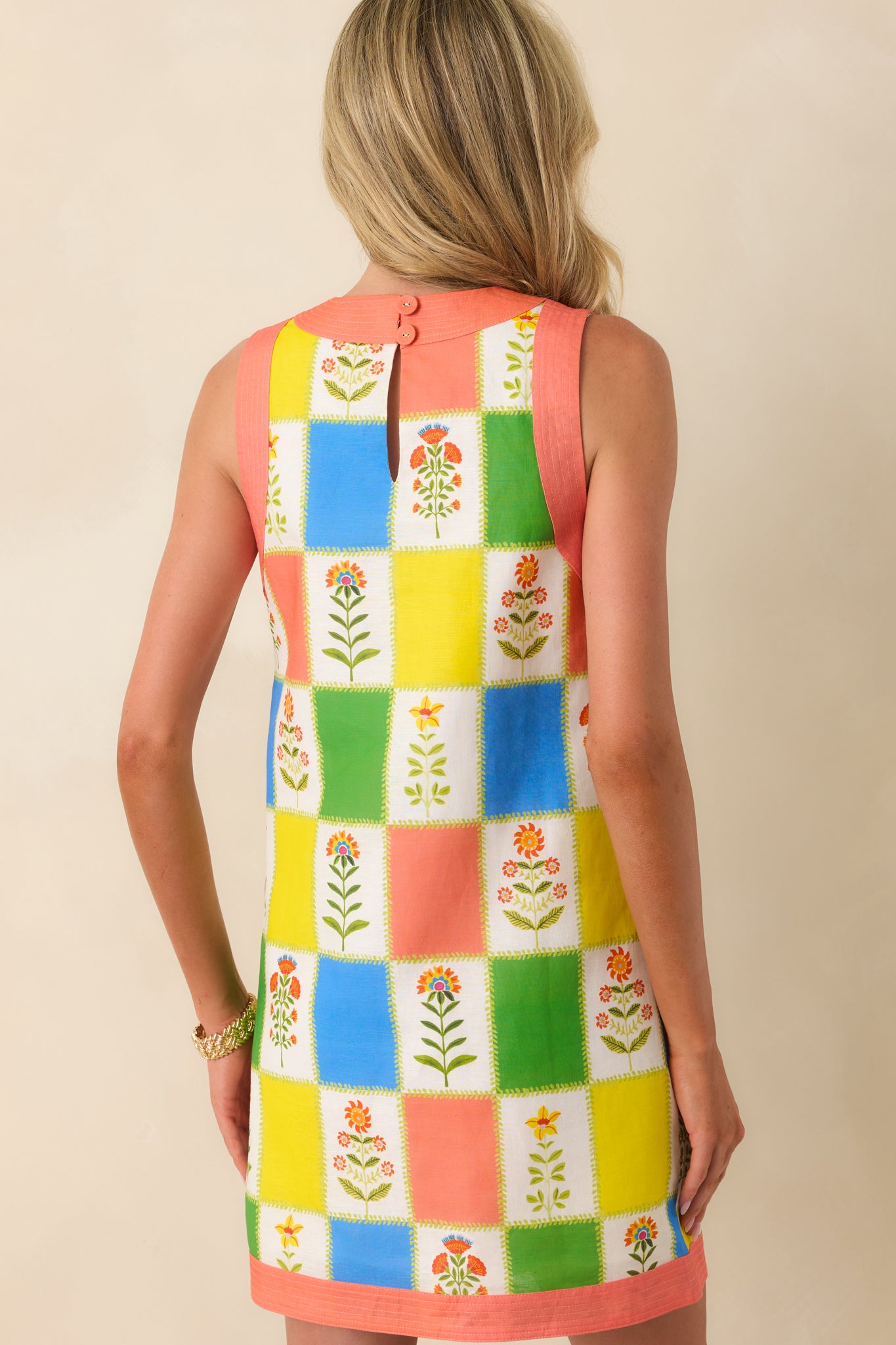 Rear view of the mini dress highlighting the continuous floral patchwork design, relaxed shift shape, sleeveless cut, and smooth, easy drape through the back.