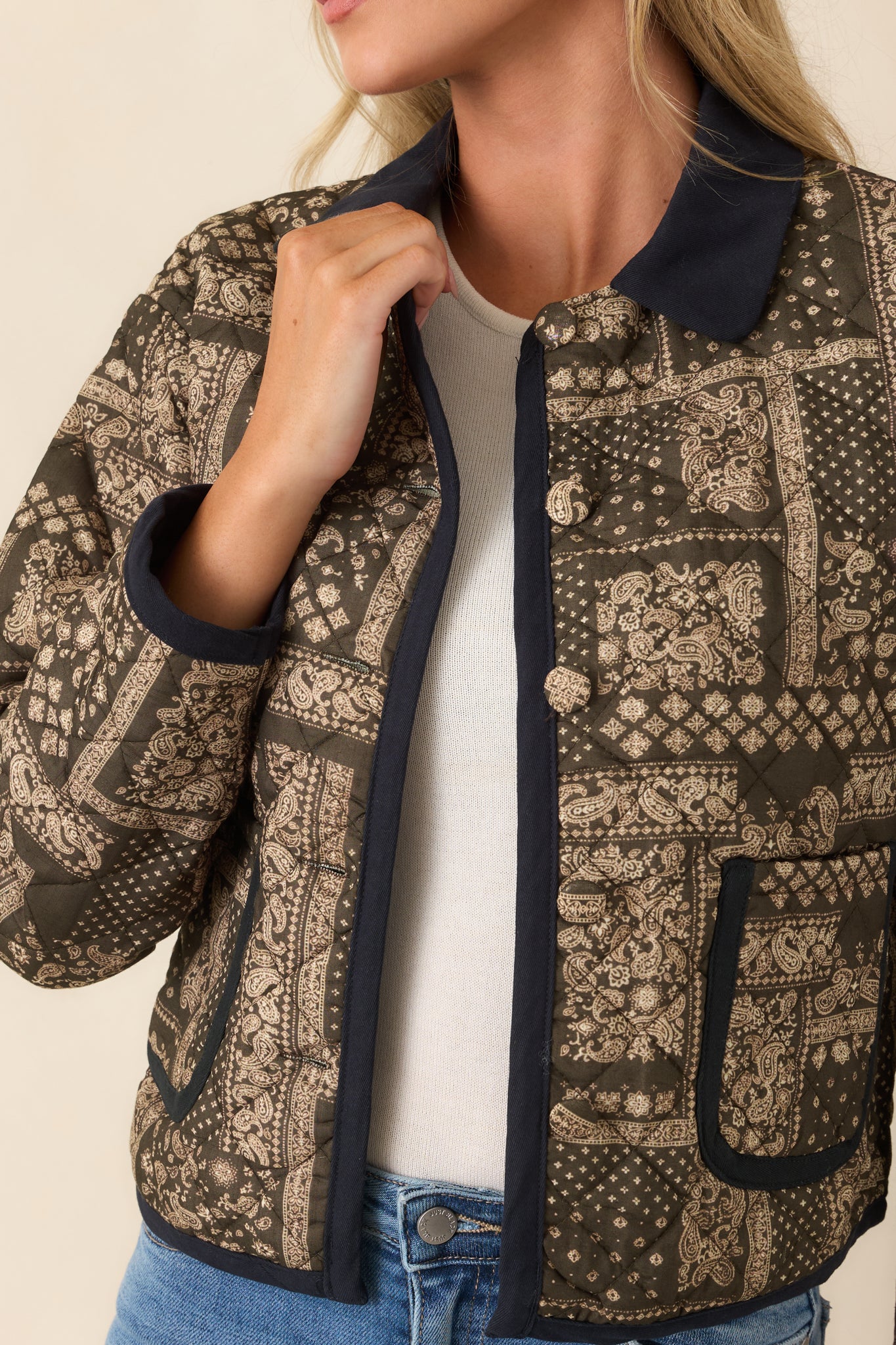 Close-up of the jacket highlighting the green and ivory paisley patchwork print, dark trim, and refined stitching details.