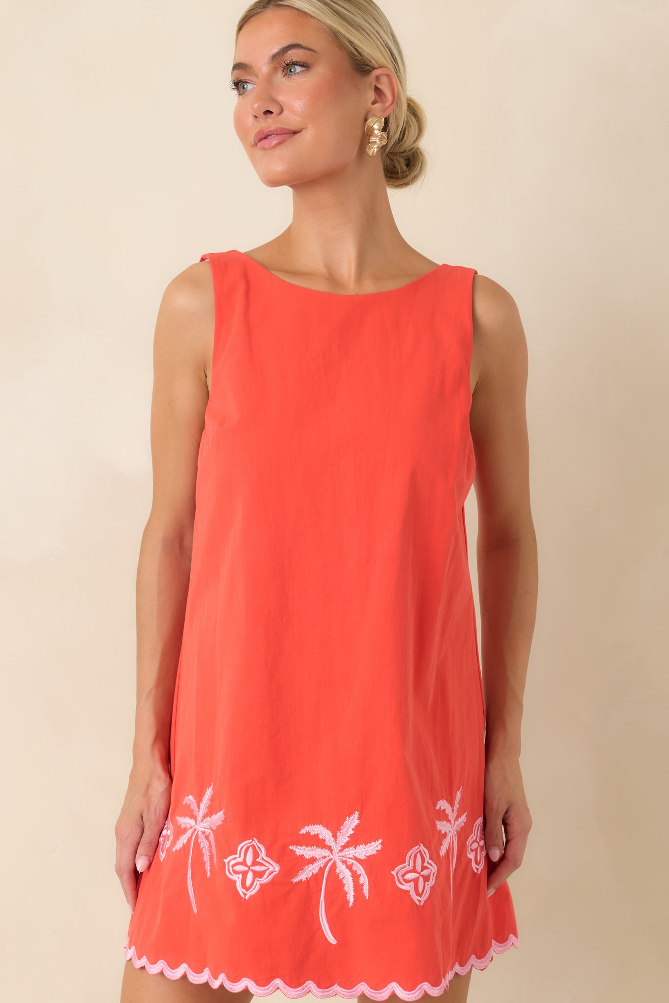 Embroidered palm tree details add a whimsical touch to the vibrant coral cotton mini dress.
