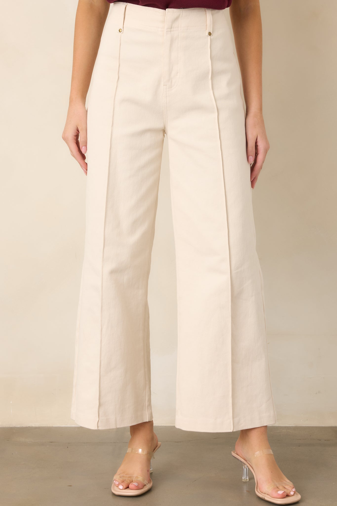 Detailed view of the pants’ high-rise waistband, belt loops, and neatly sewn front pleats.