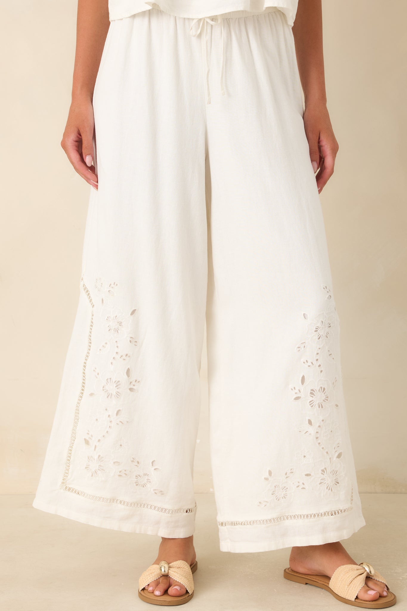 Floral embroidery and openwork trim create a decorative finish along the lower legs.