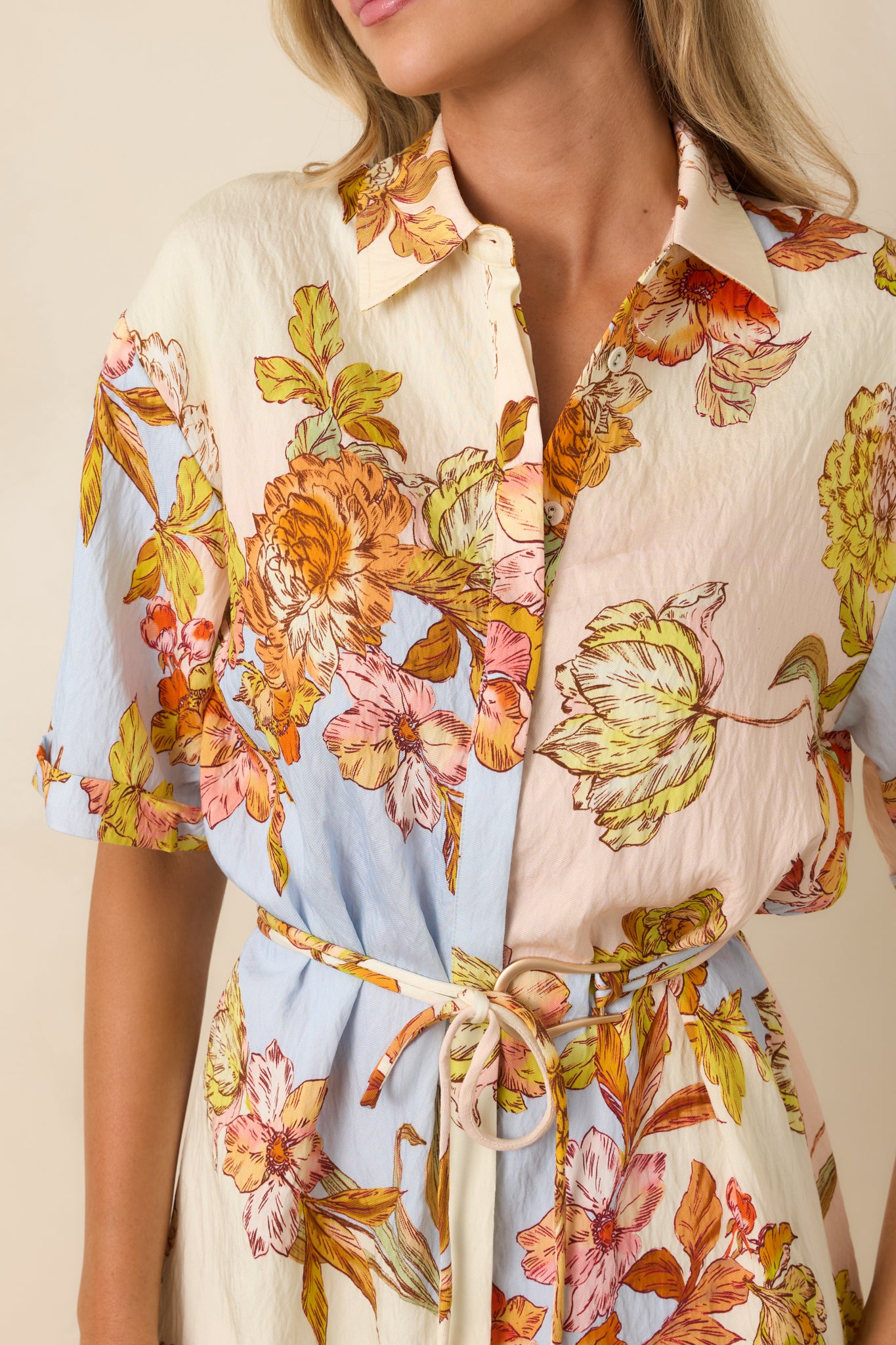 Close-up of the pastel floral print, collared neckline, and button-through front on the lightweight mini dress.