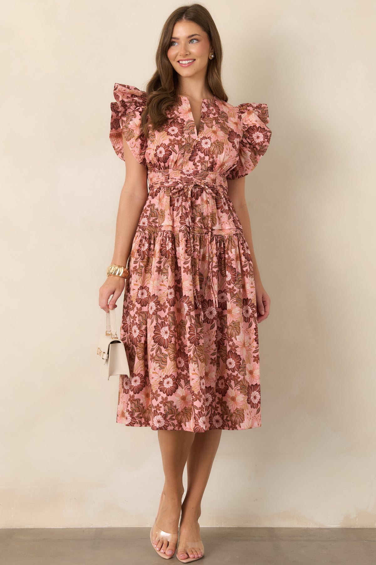 Pastel floral dress showcasing a pink and brown botanical pattern, short ruffle sleeves, V-neckline, shaped waist, and airy gathered skirt.
