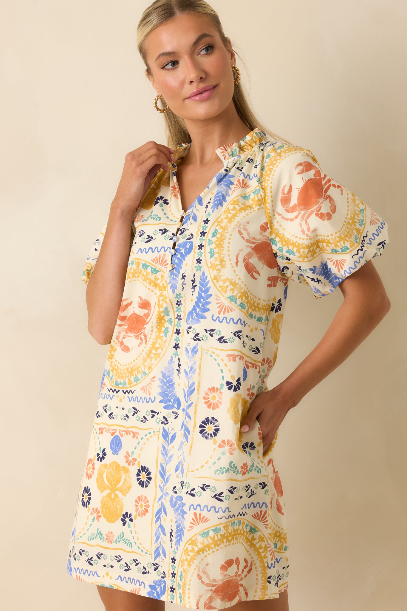 Colorful patchwork mini dress showcasing decorative button accents, a stand collar, and intricate coastal-inspired artwork.