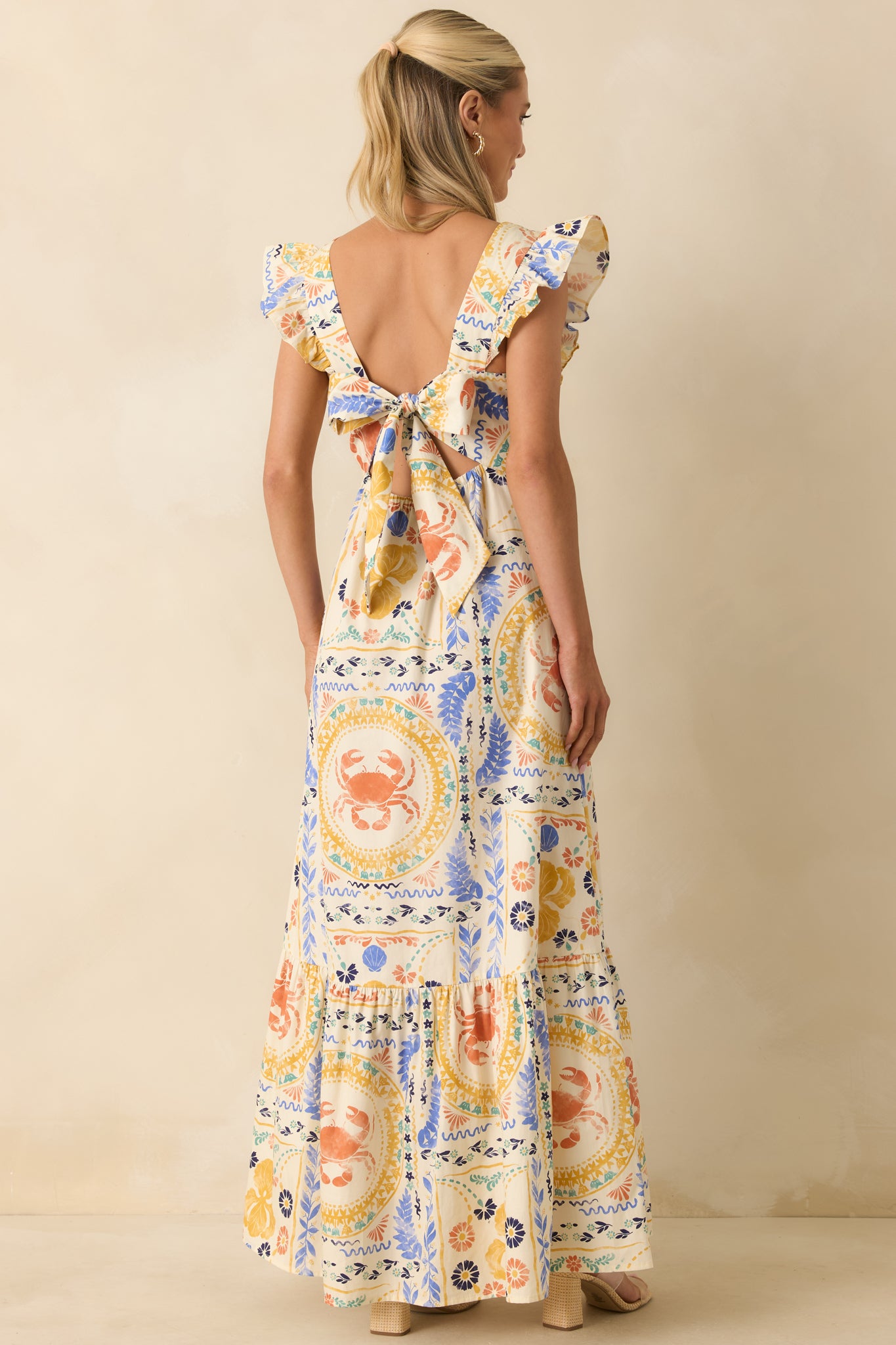 Rear view of the colorful patchwork maxi dress highlighting the open back, oversized self-tie bow, and tiered skirt.