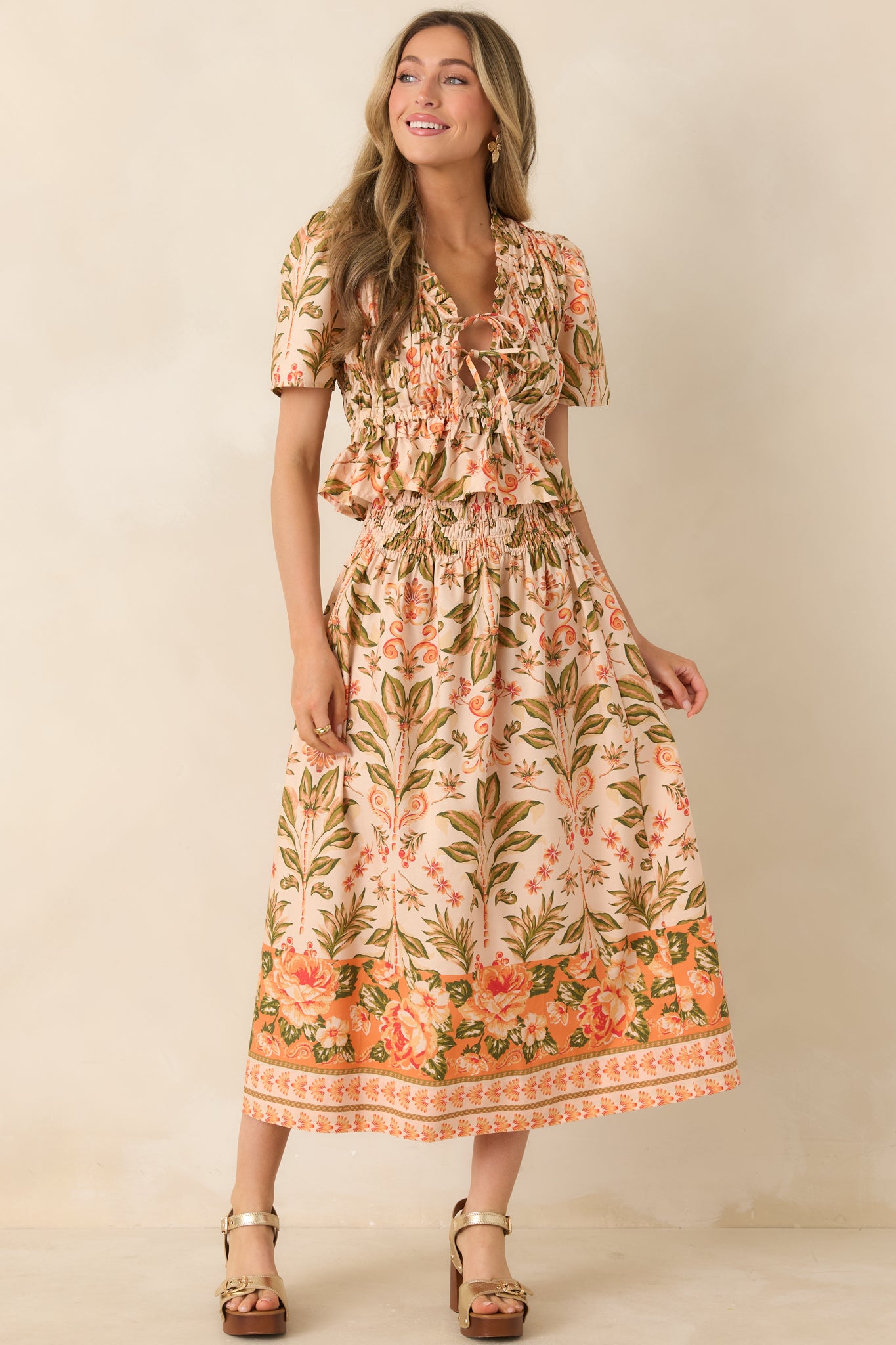 Peach and green floral top with smocked bodice and ruffled V-neckline.