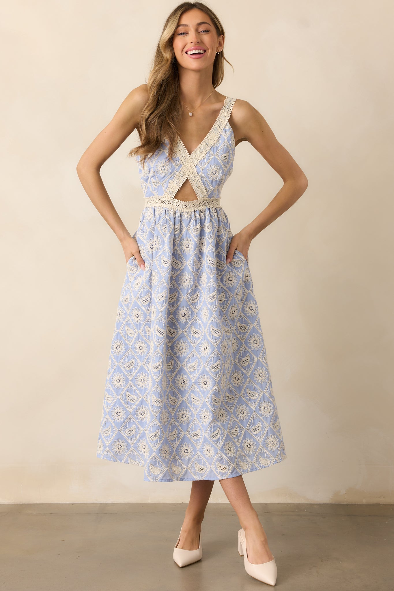 A beautiful periwinkle dress adorned with lace embroidery detailing, featuring a v-neckline, a cutout in the center of the bodice, and adjustable straps for a customized fit.