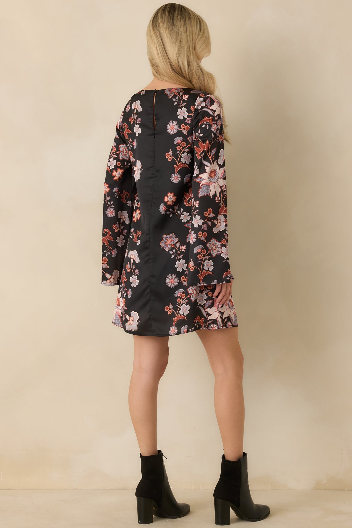 Back view of periwinkle, ivory, and rust floral mini dress with a smooth satin finish and dramatic sleeves.

