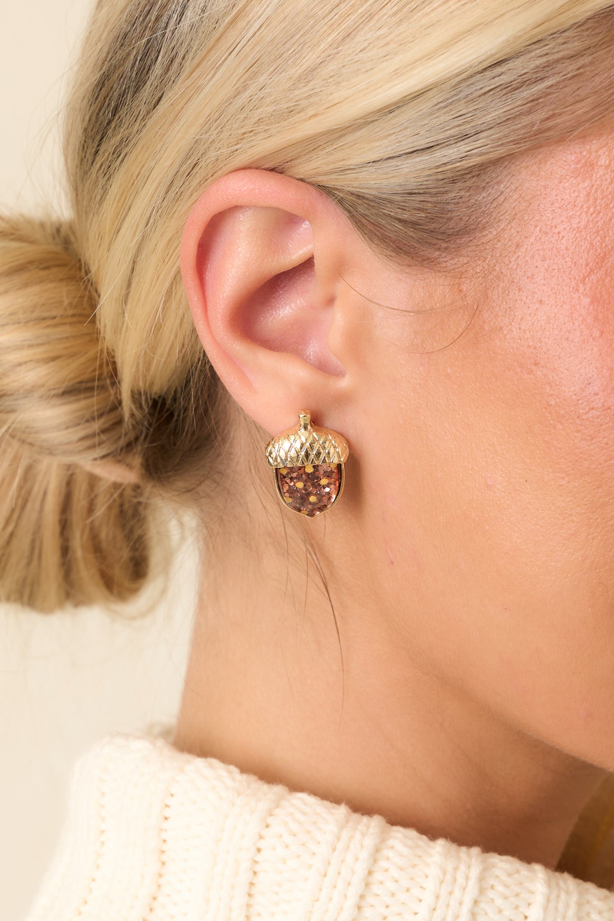 Petite acorn stud earrings feature rich brown centers with reflective gold and copper glitter, finished with textured gold-tone caps.