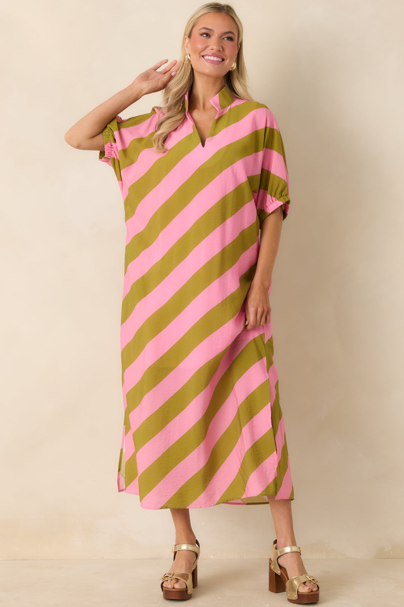 Pink and olive green maxi dress with split neckline, short sleeves, and flowing skirt.
