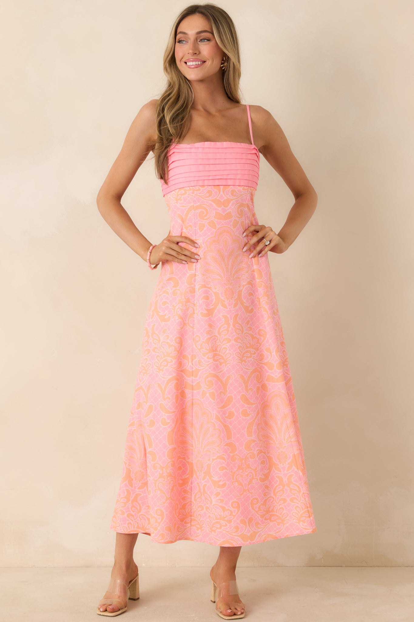 Pink and orange midi dress with adjustable spaghetti straps, a structured pleated bust, and a lightweight flowing skirt