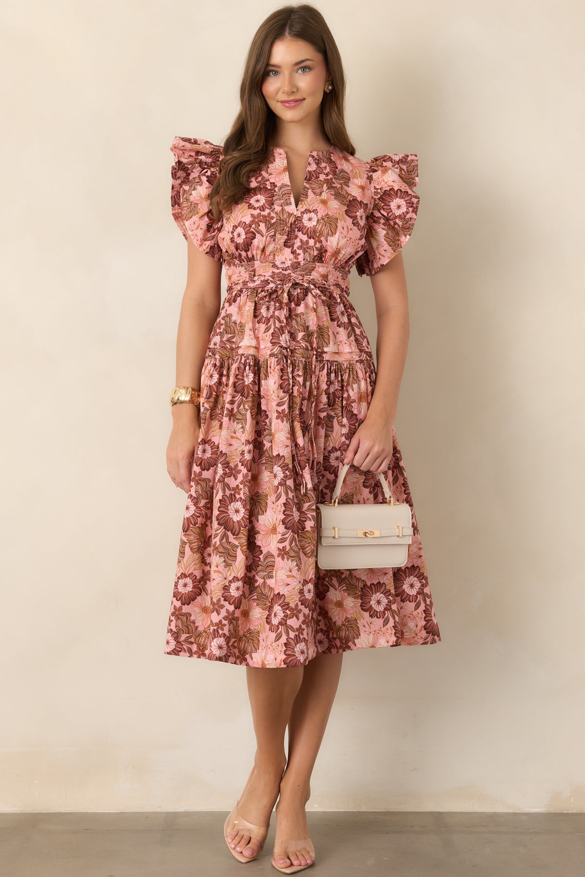 Flowing floral-print dress in pastel pink and brown, featuring a flattering V-neckline, ruffled short sleeves, cinched waist, and gathered skirt.