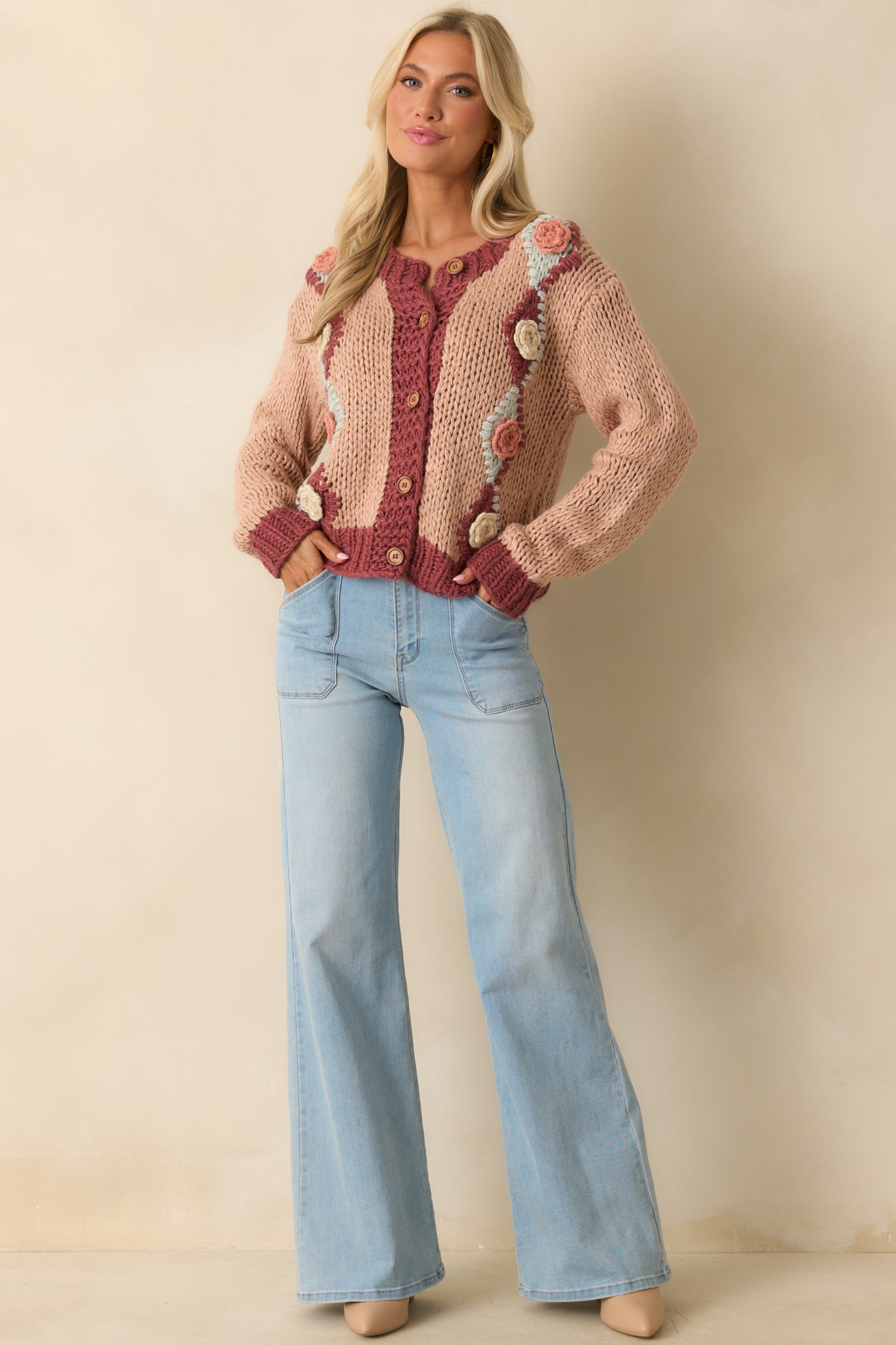 Pink chunky knit cardigan highlighting 3D floral crochet appliqués on the front.