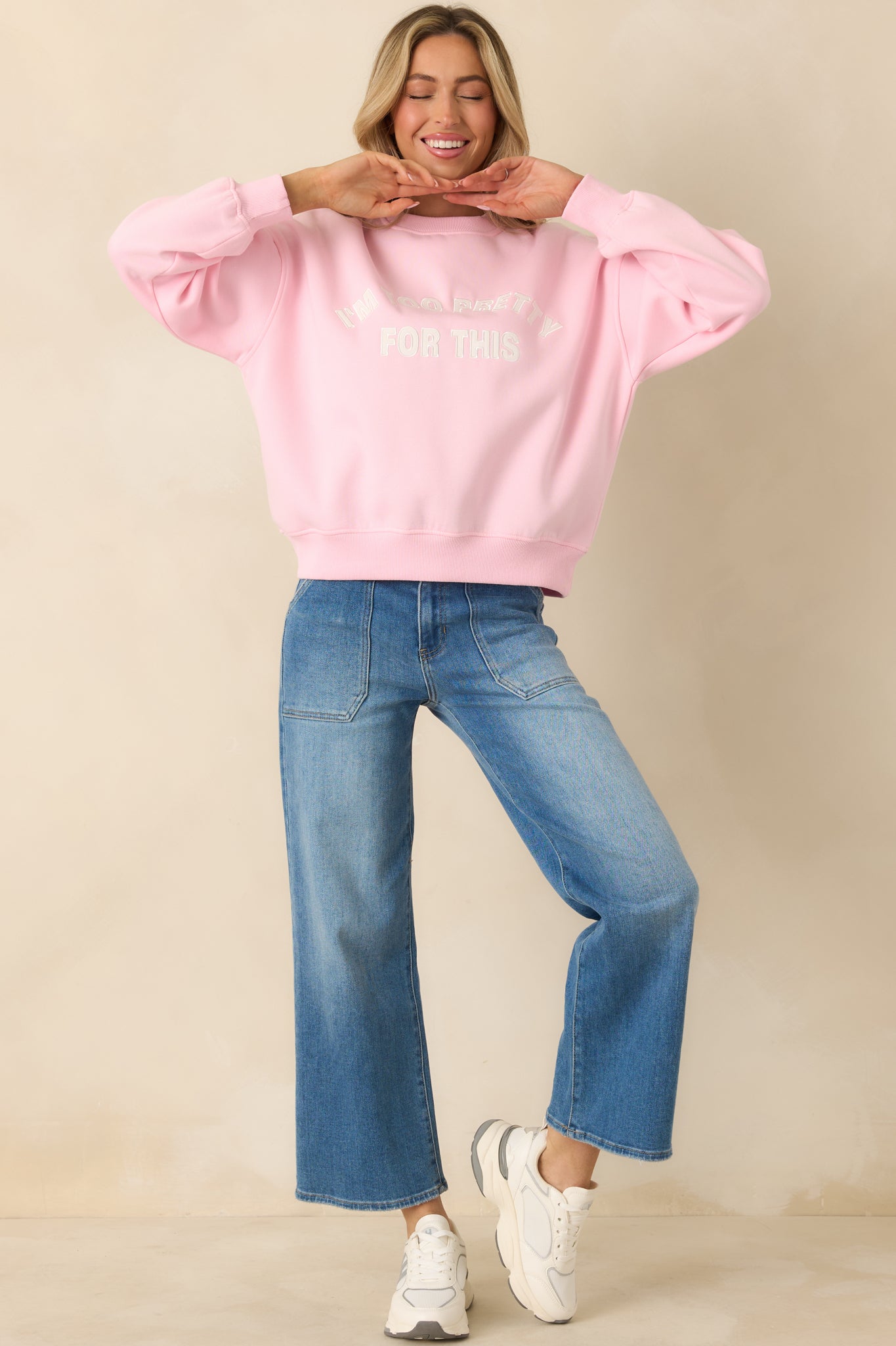Pink crewneck sweatshirt with relaxed fit, ribbed trim, and centered embroidered front text.