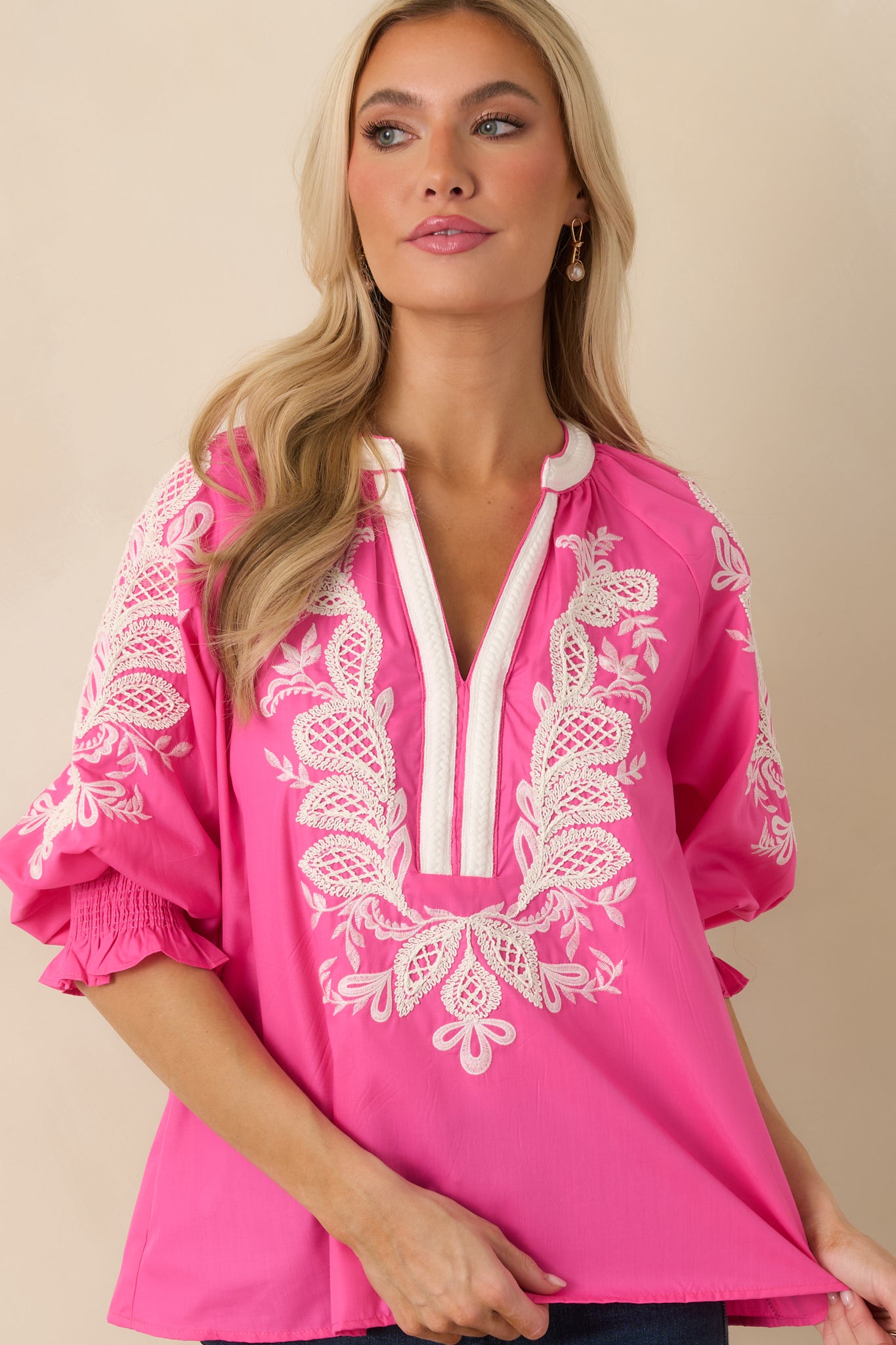 Detailed view of the pink embroidery highlighting the textured stitching across the fabric.