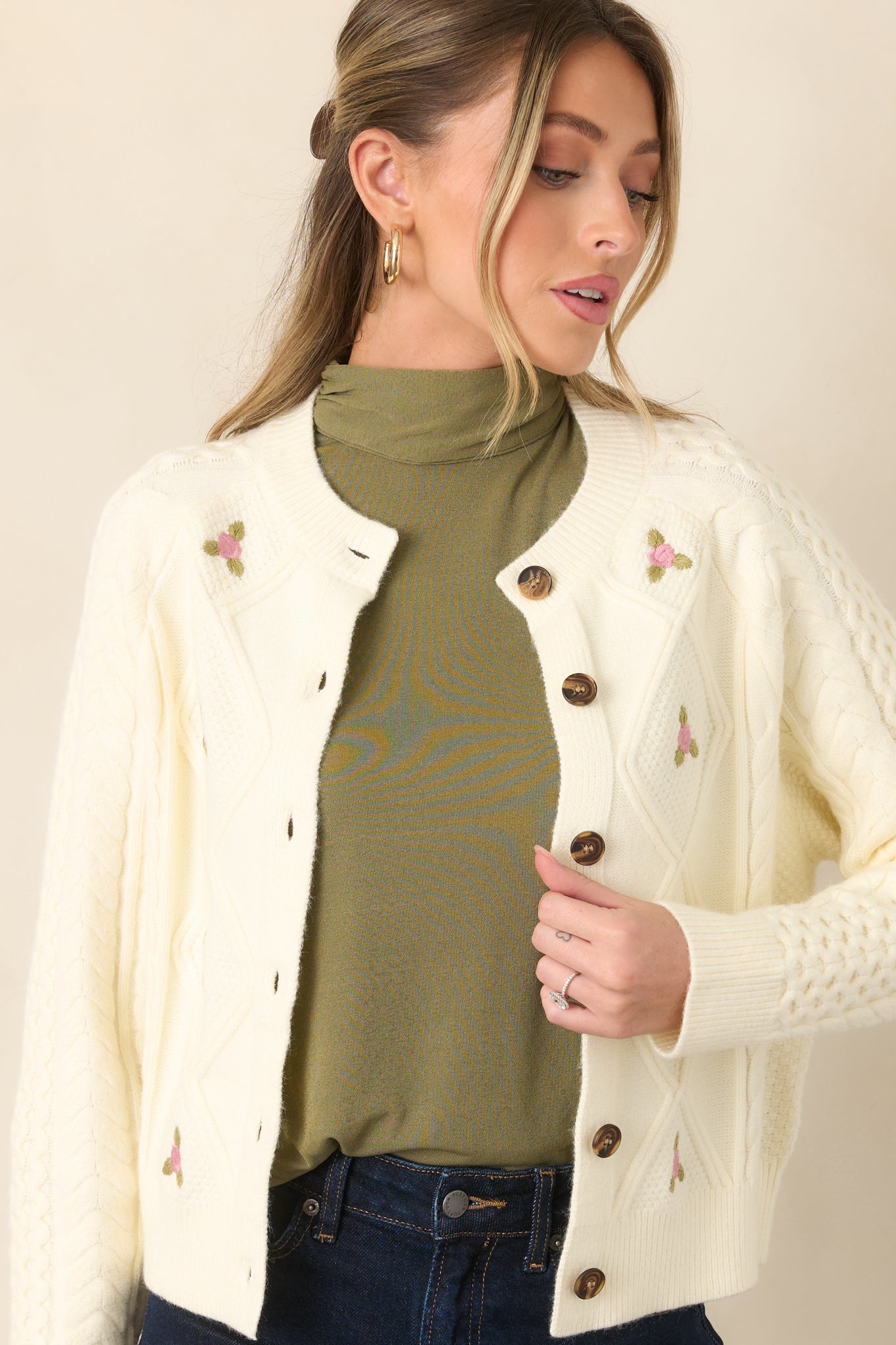 Cardigan showcasing the delicate pink floral embroidery scattered across the textured knit, with ribbed cuff detailing.