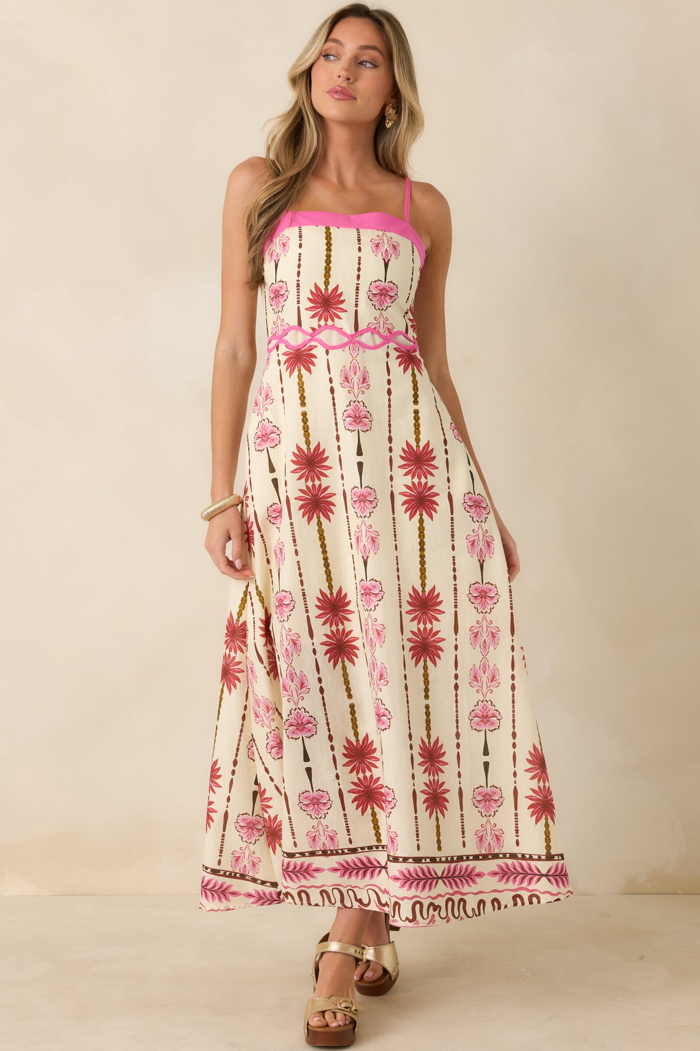 Pink and cream floral maxi dress designed with contrast trim, decorative waist cutout detailing, and a breezy silhouette.